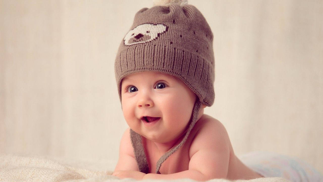 En smilende baby i en brun barette Wallpaper