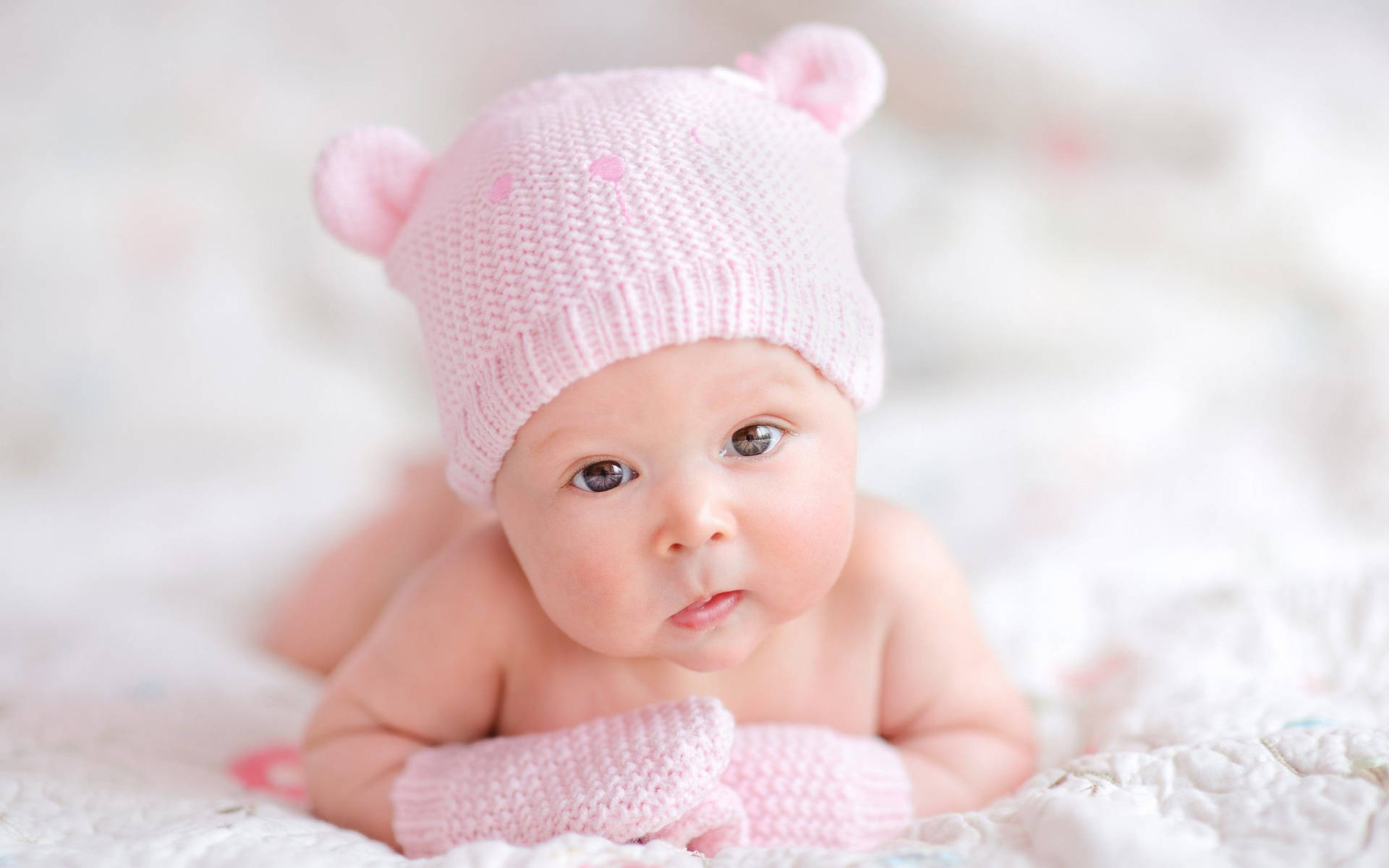 "A baby with a pink bear ear bonnet looking wide-eyed and ready to explore the world!" Wallpaper