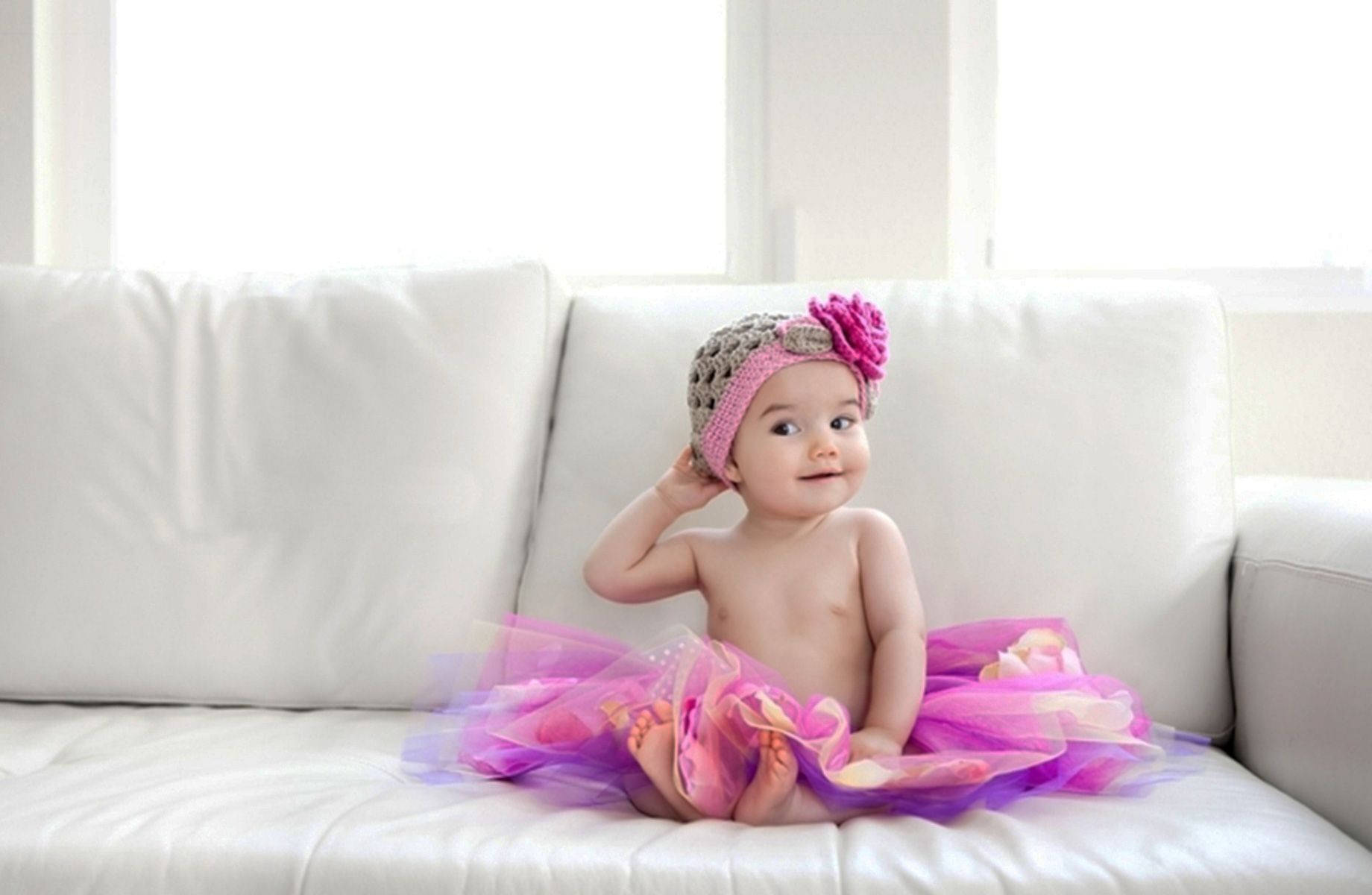Adorable Baby Sitting on Cozy Sofa Wallpaper