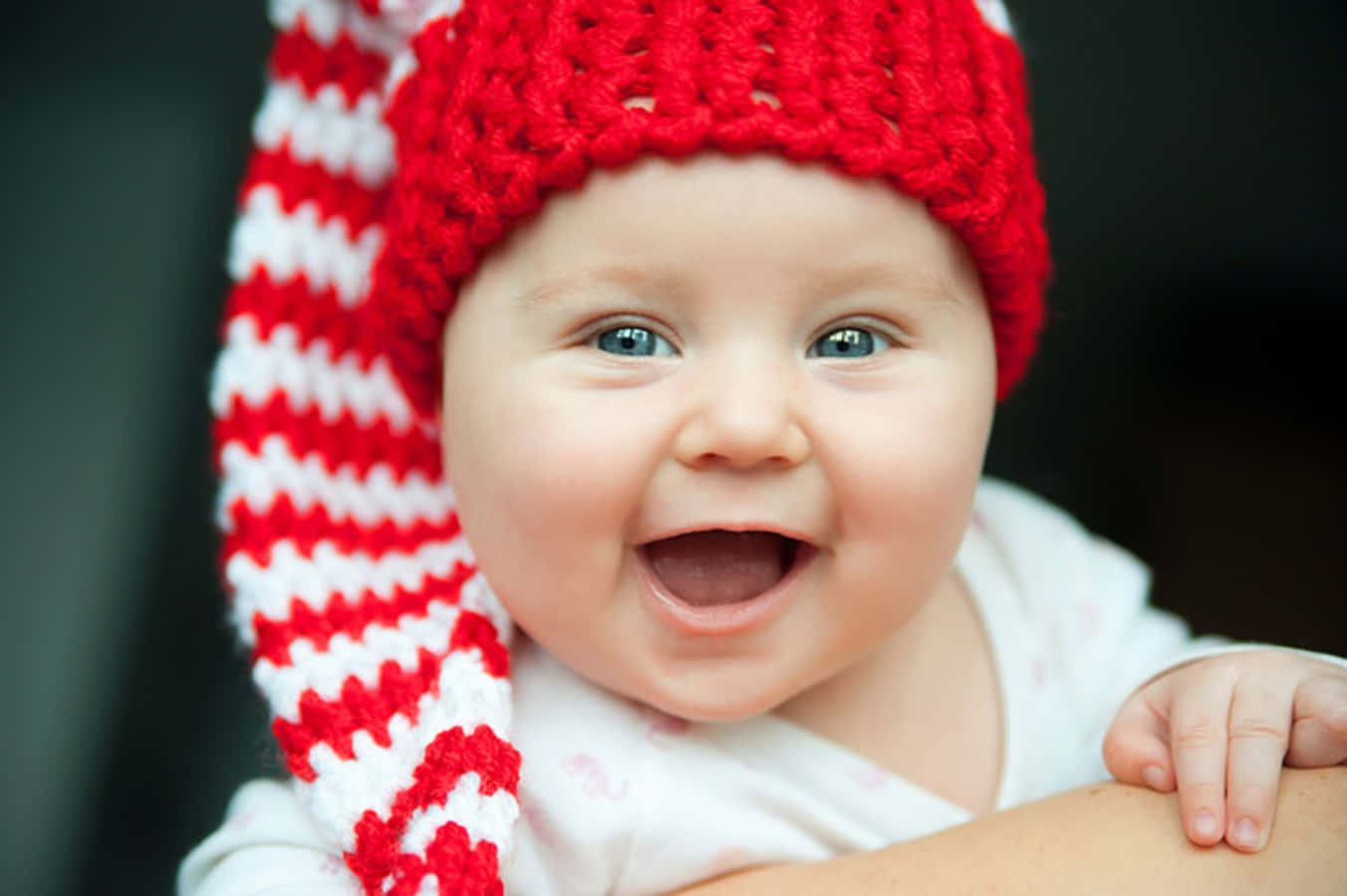 Imagende Un Bebé Sonriendo Con Un Gorro Rojo.