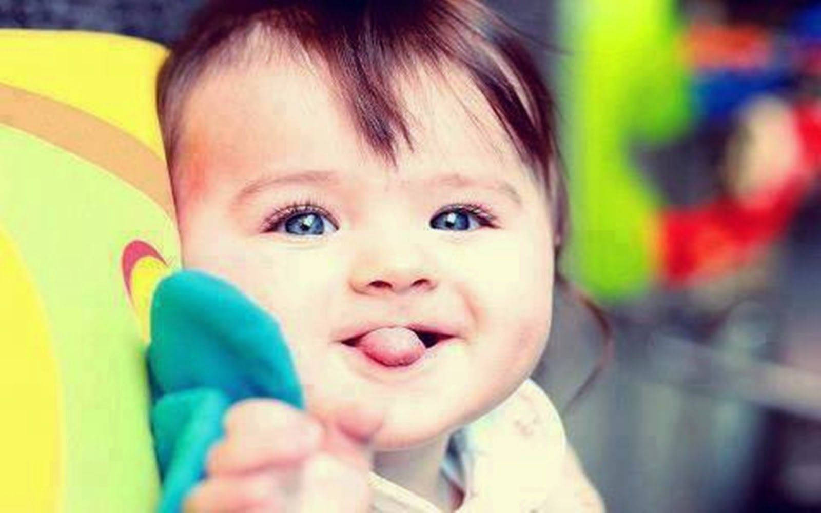 En baby smilende og stikke deres tunge ud på legefuld vis. Wallpaper