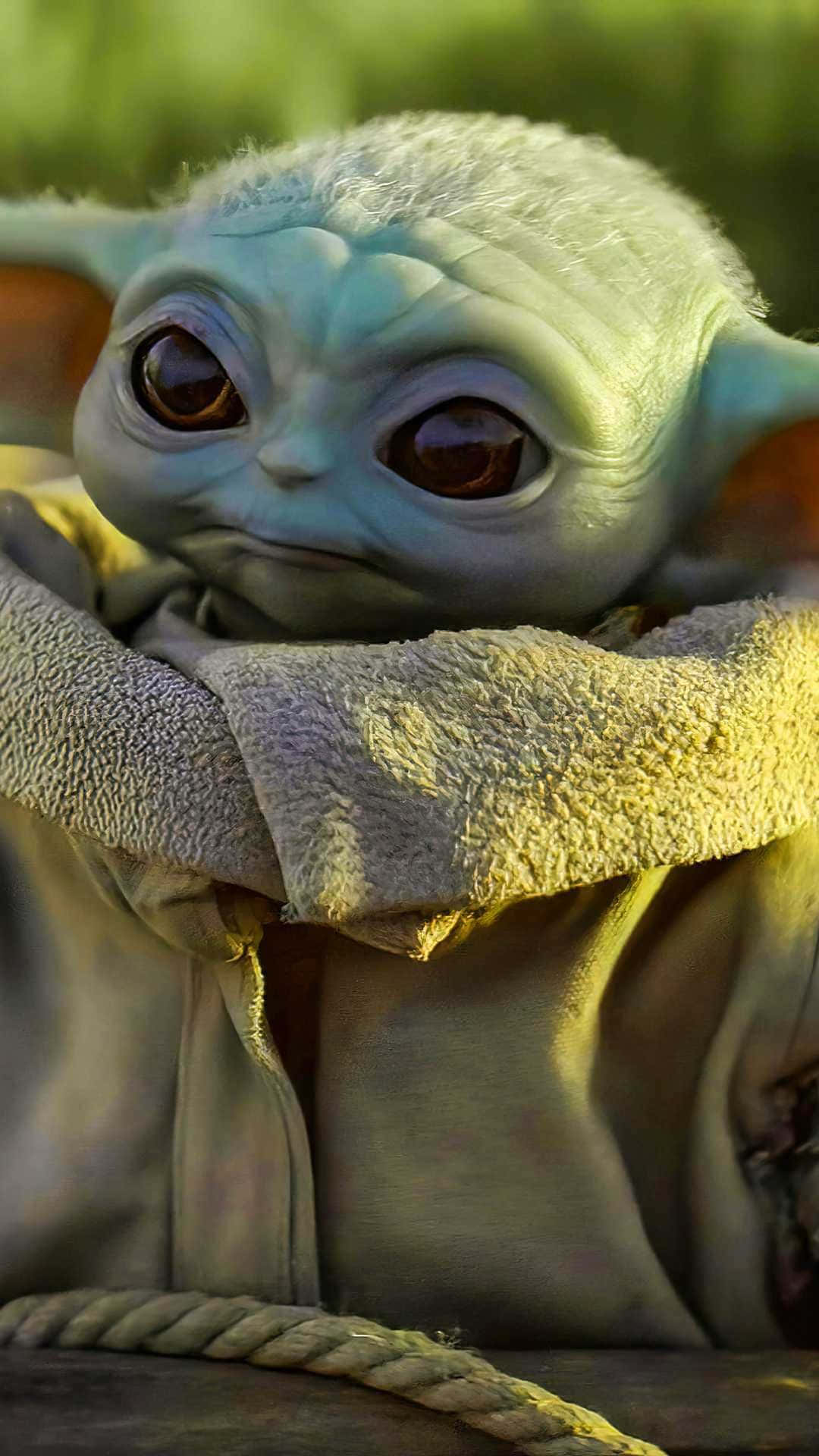 The Baby Yoda Is Sitting On A Wooden Table Wallpaper