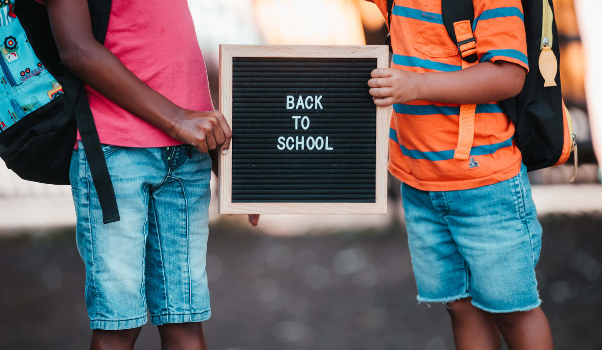Two Children Holding A Back To School Sign Wallpaper