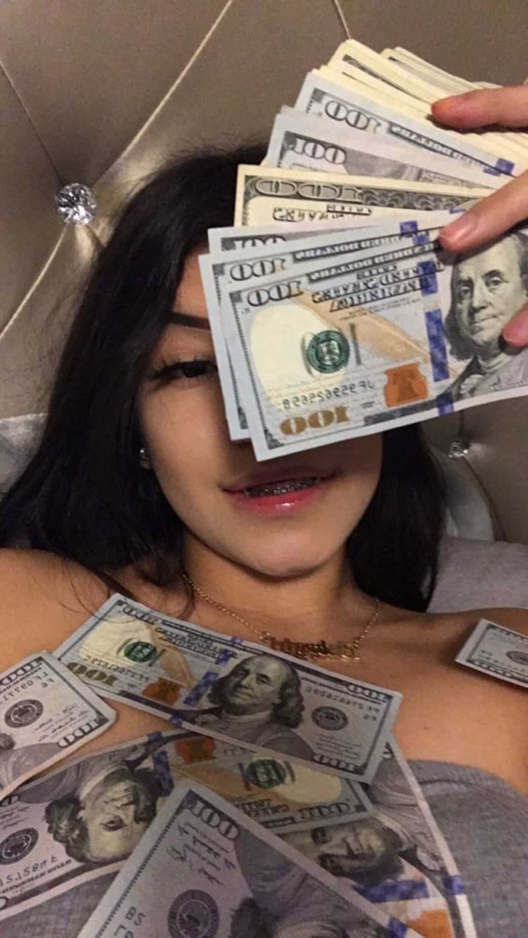 En pige, der ligger på en seng med et stort beløb penge. Wallpaper