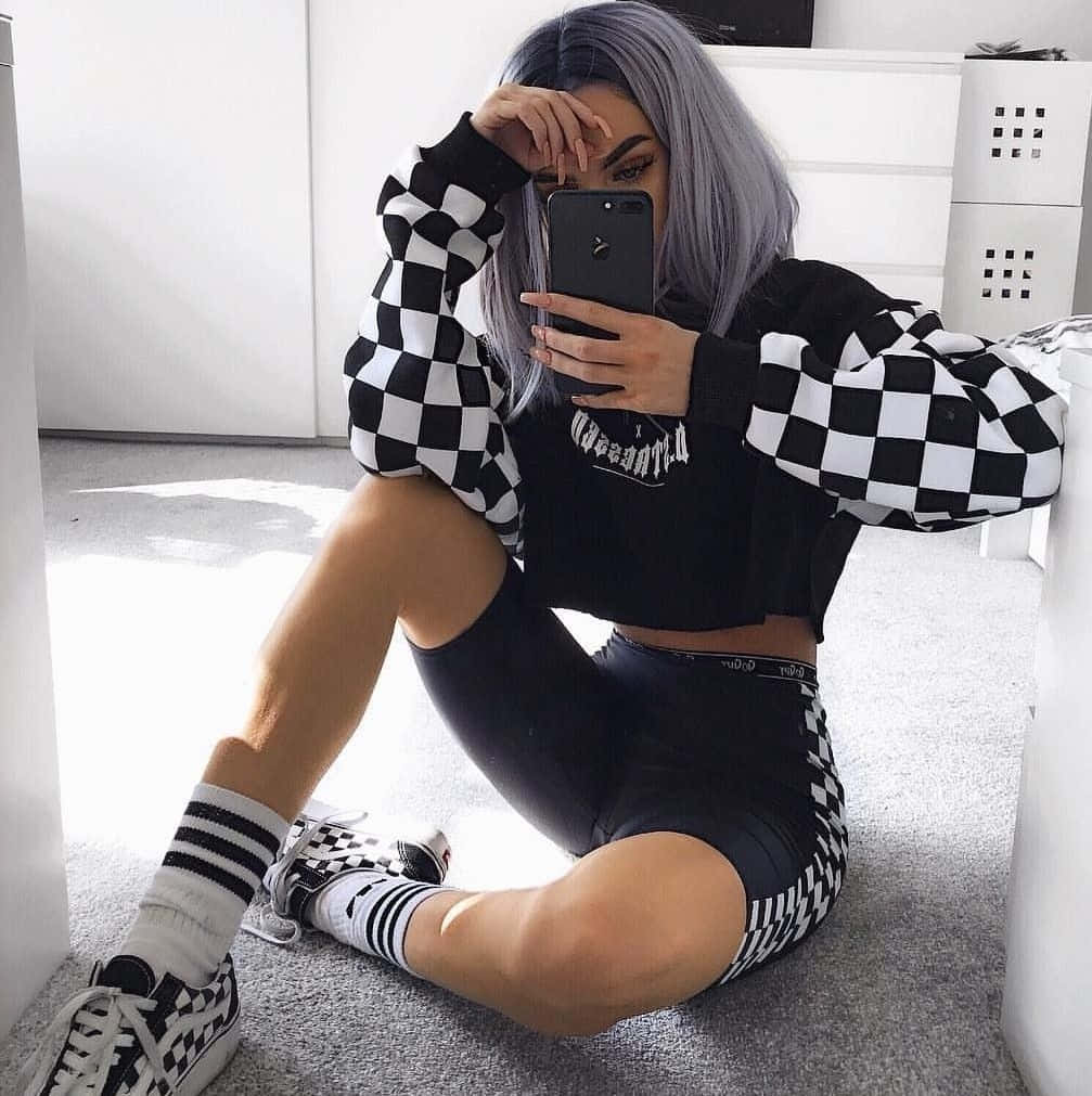 A Woman Wearing A Checkered Sweatshirt And Sneakers