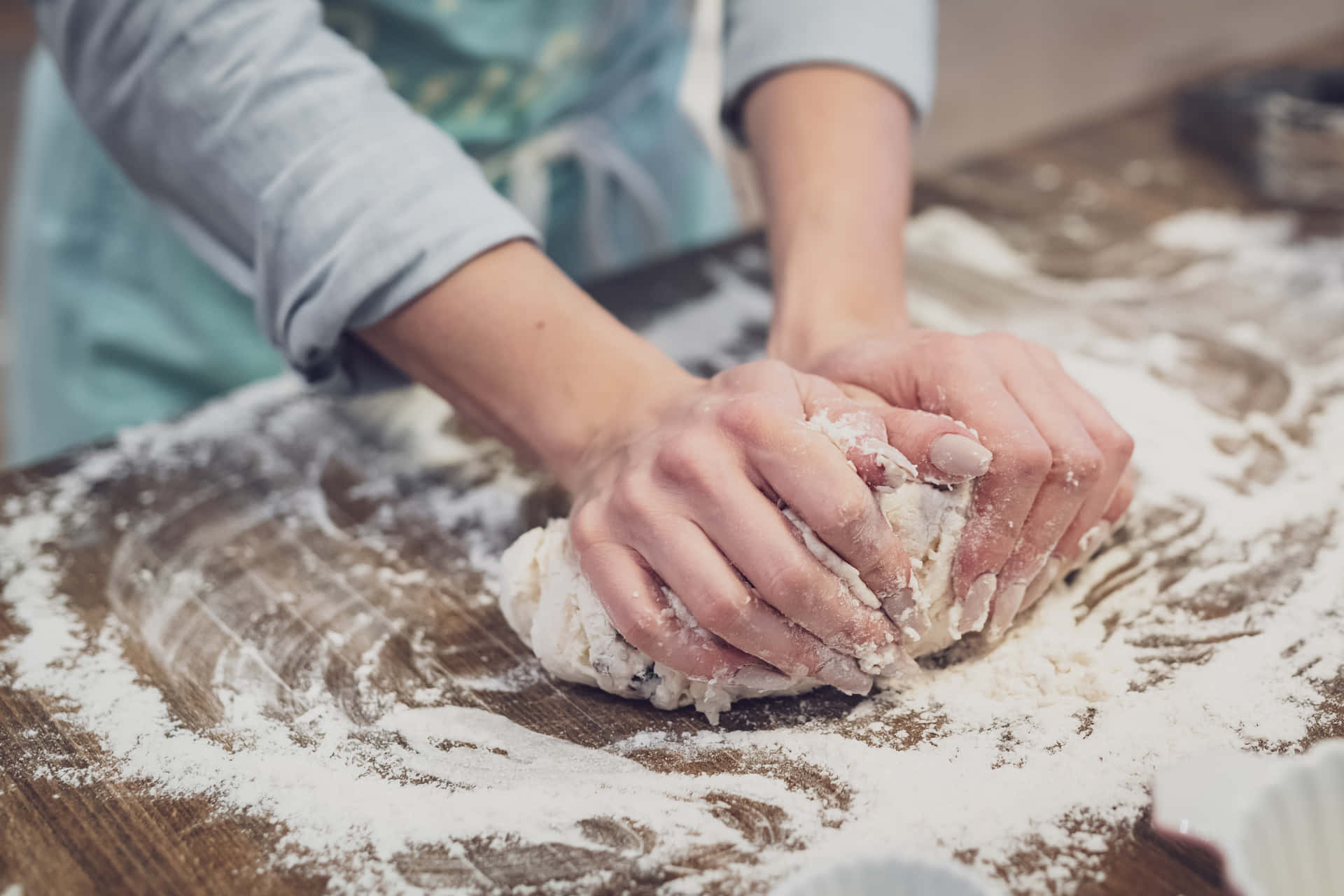 A Woman Is Kneading Dough On A Wooden Table