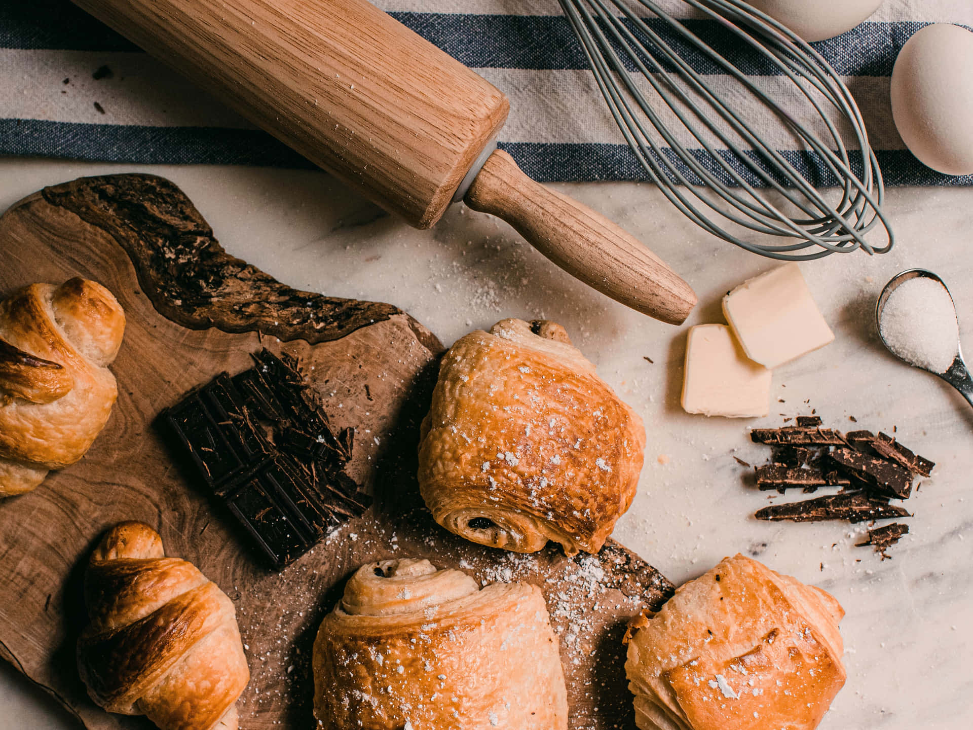 A Wooden Board With Croissants, Chocolate, And Other Baked Goods