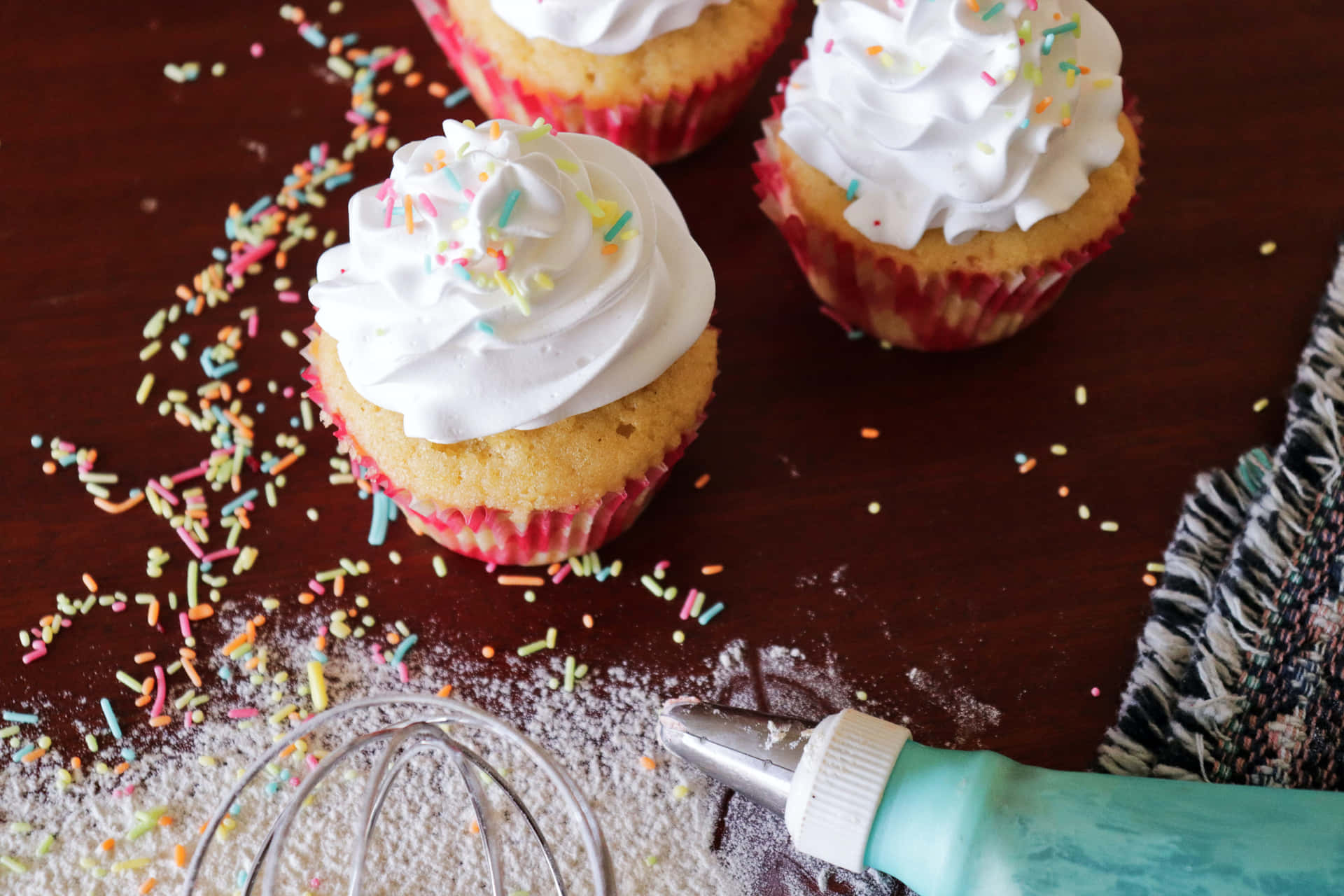 A Table With Cupcakes And A Whisk