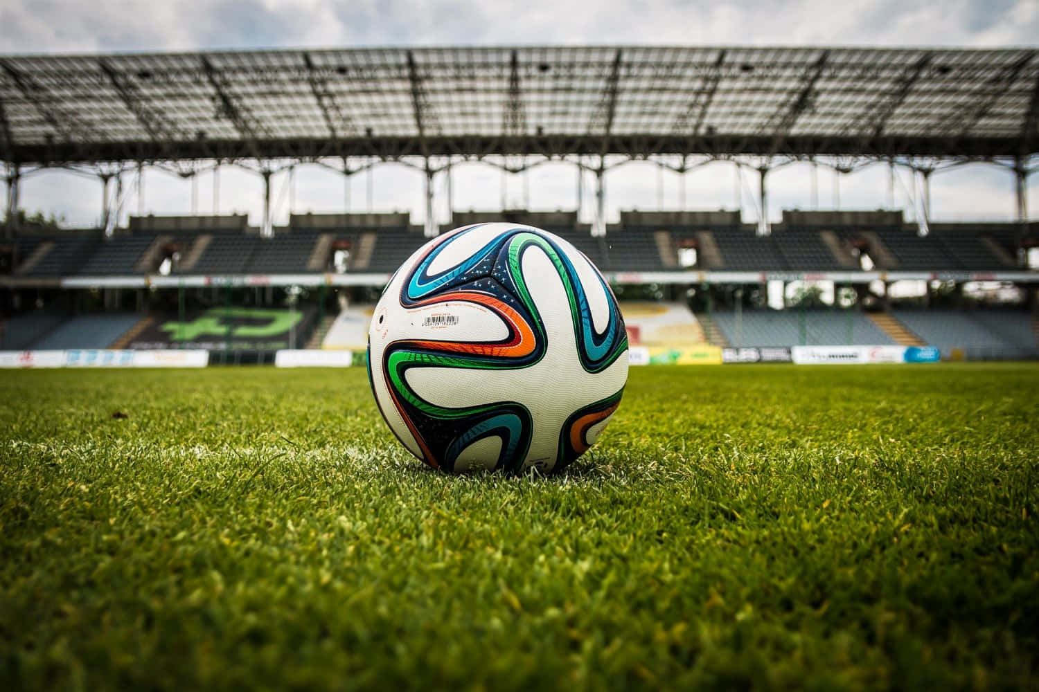 A soccer ball lies on a grassy field, ready for kick-off.