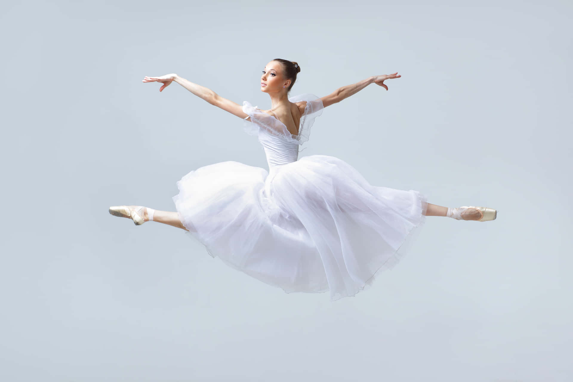A Young Ballerina In White Dress Is Jumping