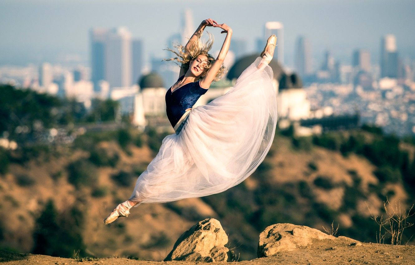Effortless Elegance: A Ballet Dancer in Mid-Air Split Pose Wallpaper