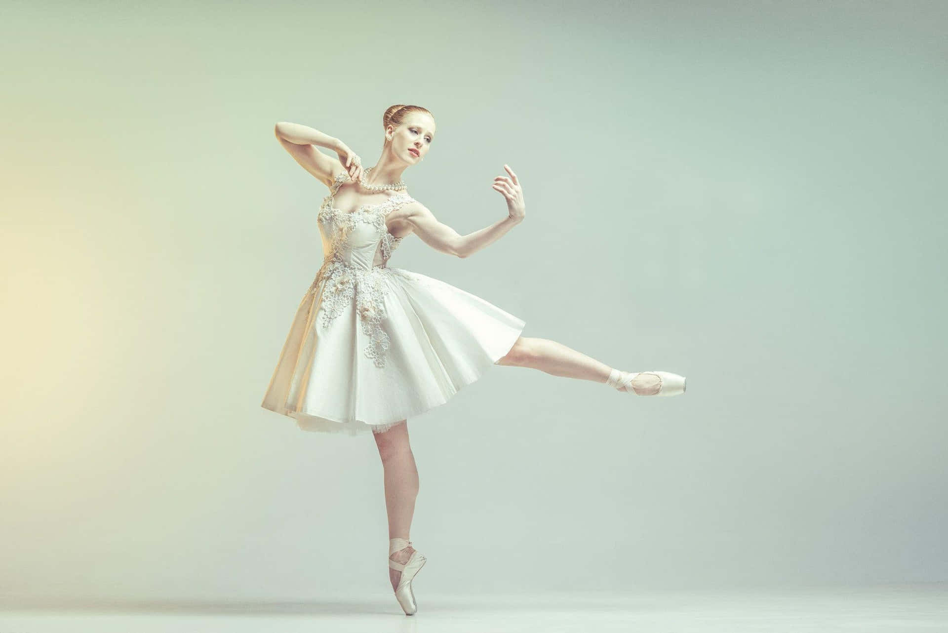 A Young Ballerina In A White Dress Is Posing