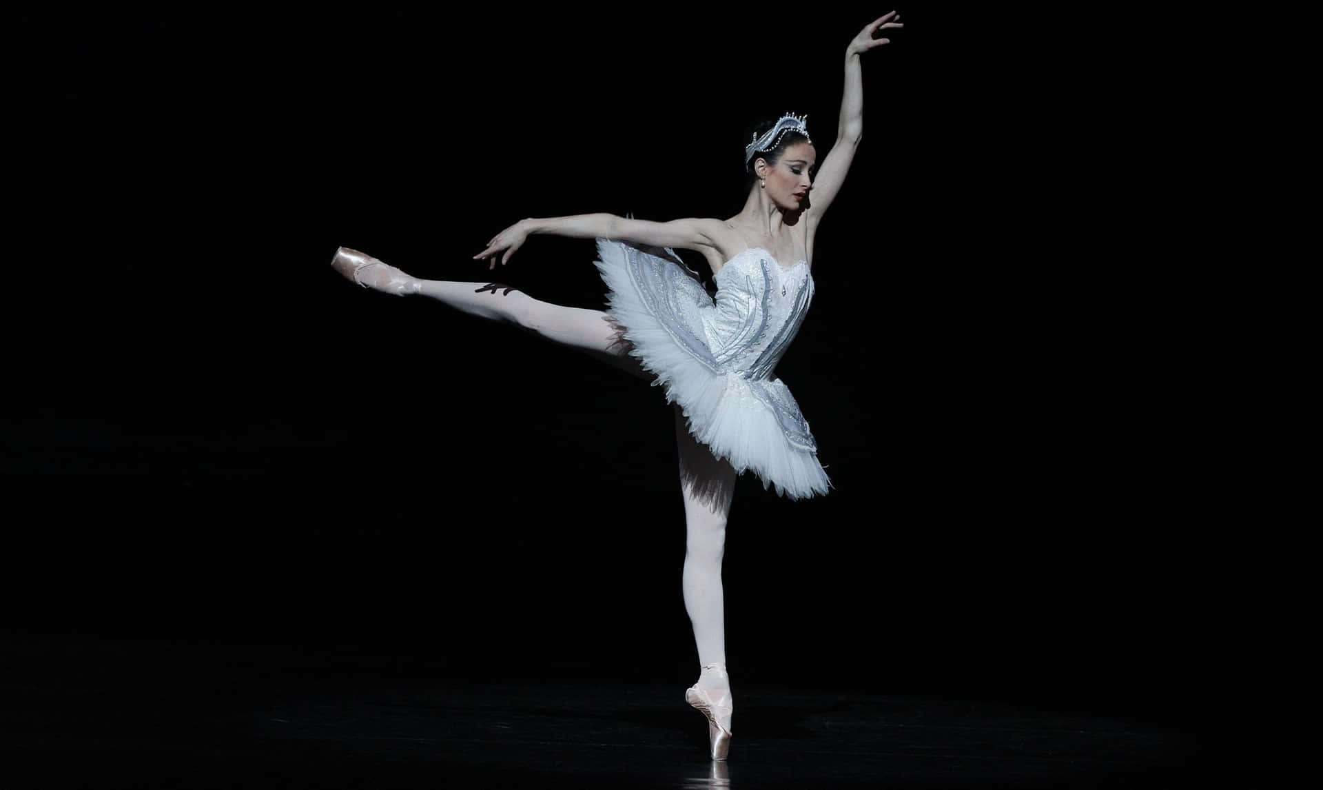 A Female Ballet Dancer In White Tutu On A Black Background