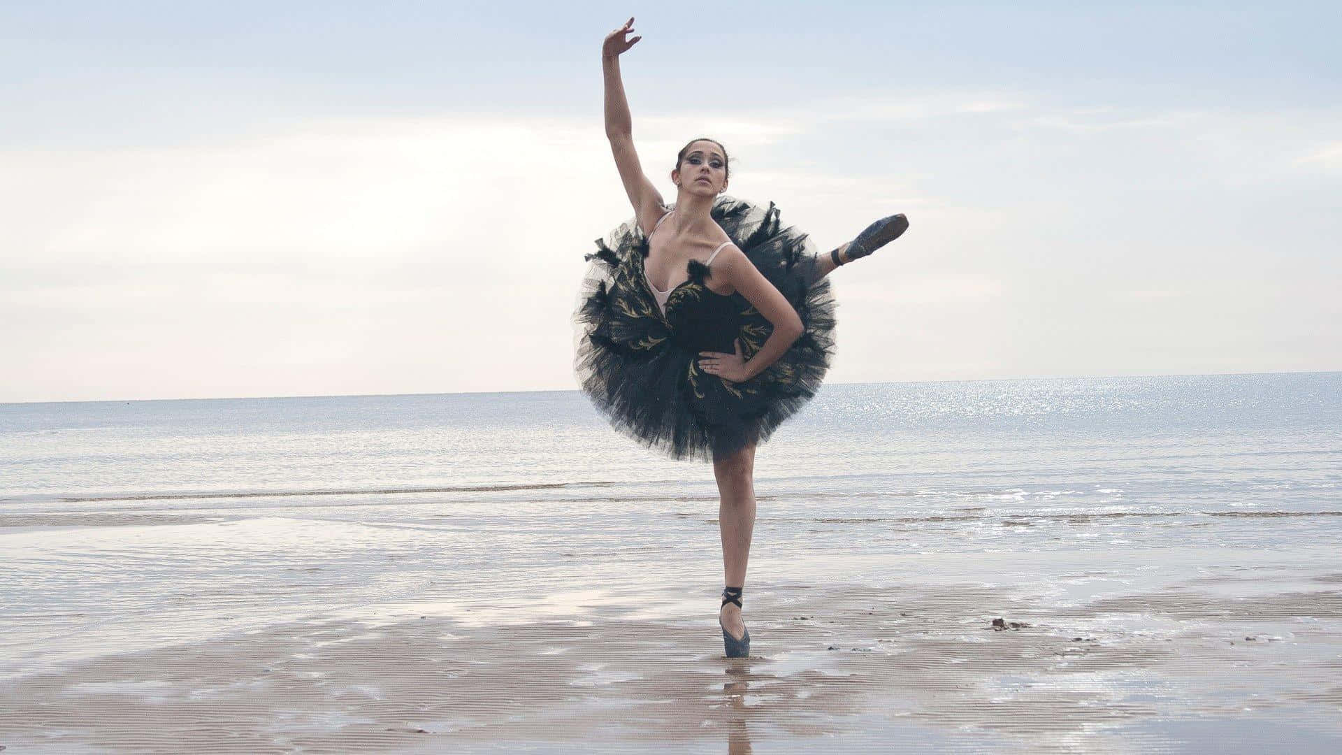 A Woman In Black Ballet Tutu Is Dancing On The Beach
