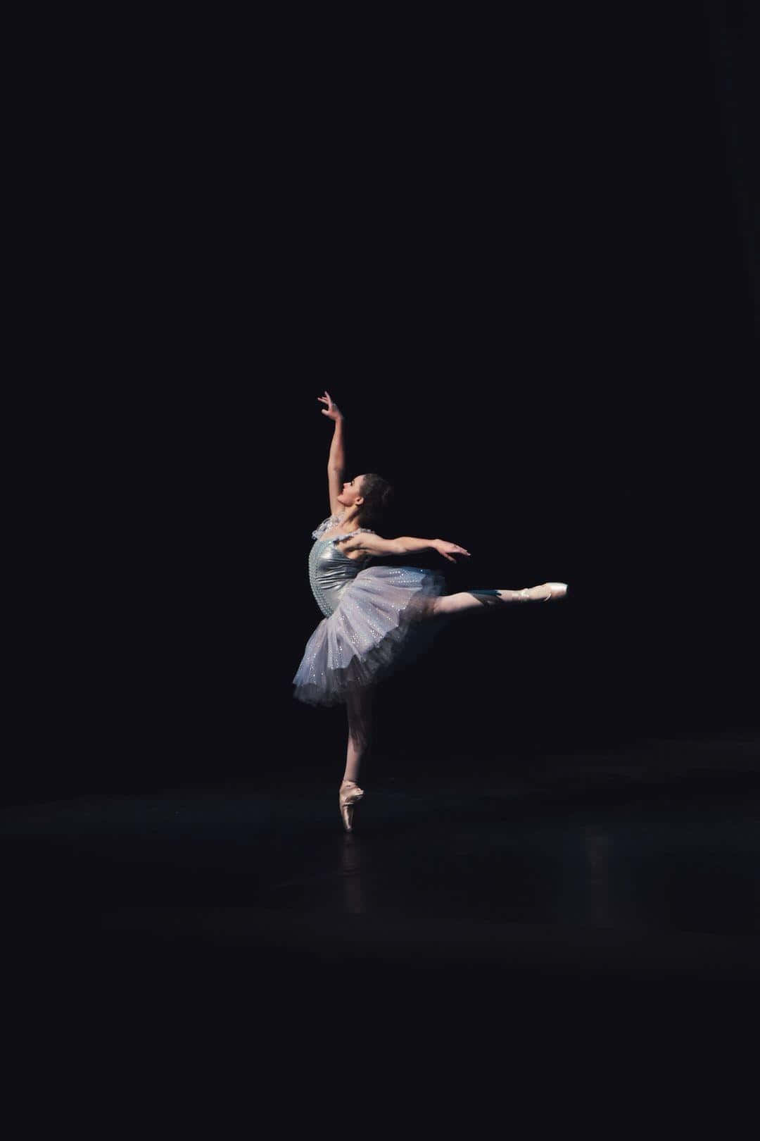 A Young Ballerina In A Tutu On A Dark Stage
