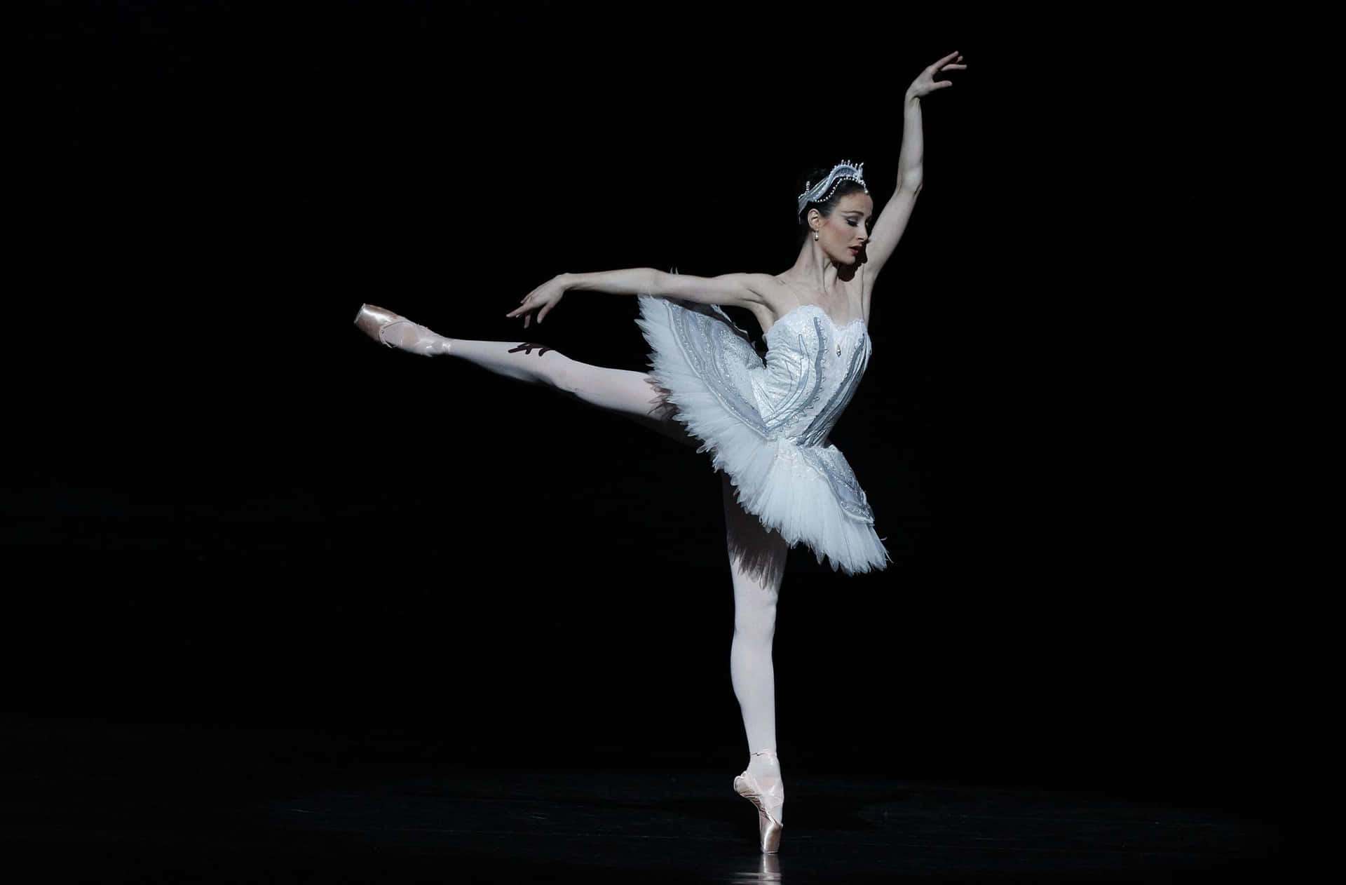 A White Ballerina Is Performing On A Black Stage