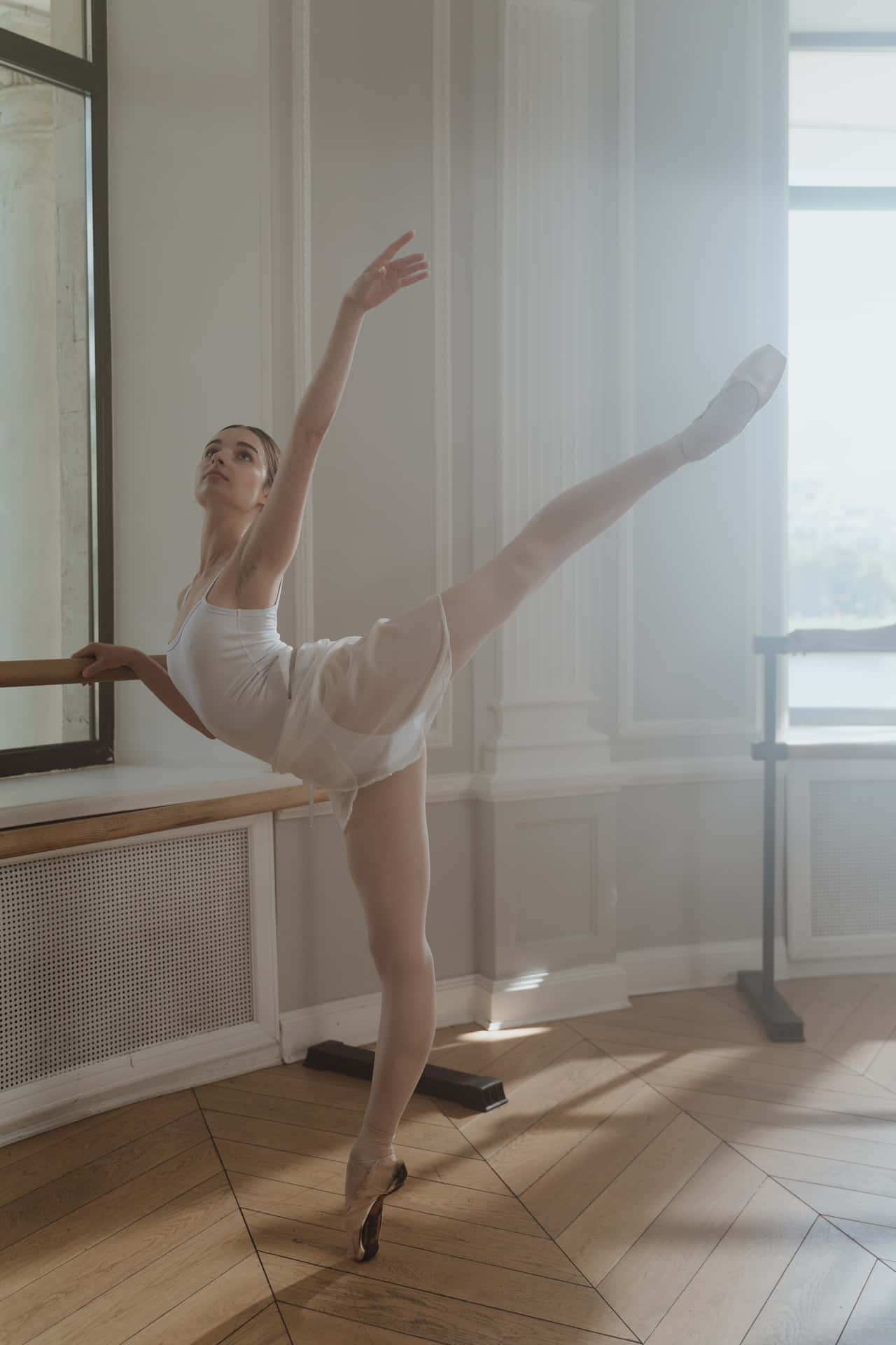 En ung balletdanser øver sig i et værelse tæt på et vindue Wallpaper