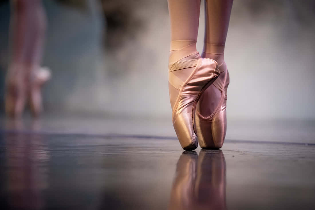 Dancer effortlessly gliding across a stage in a pair of pointe shoes. Wallpaper