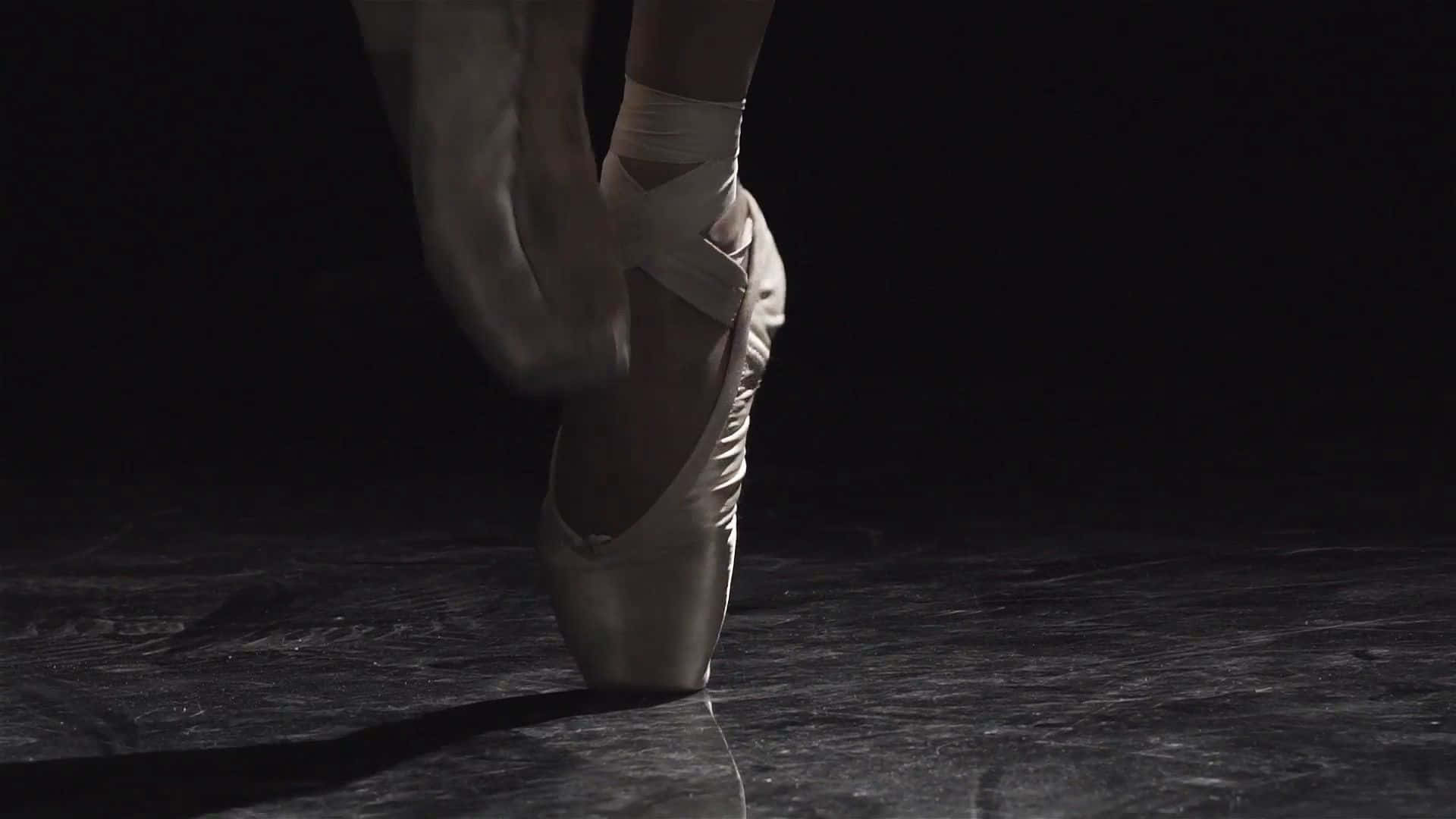 A Ballet Dancer Is Standing On A Dark Floor Wallpaper