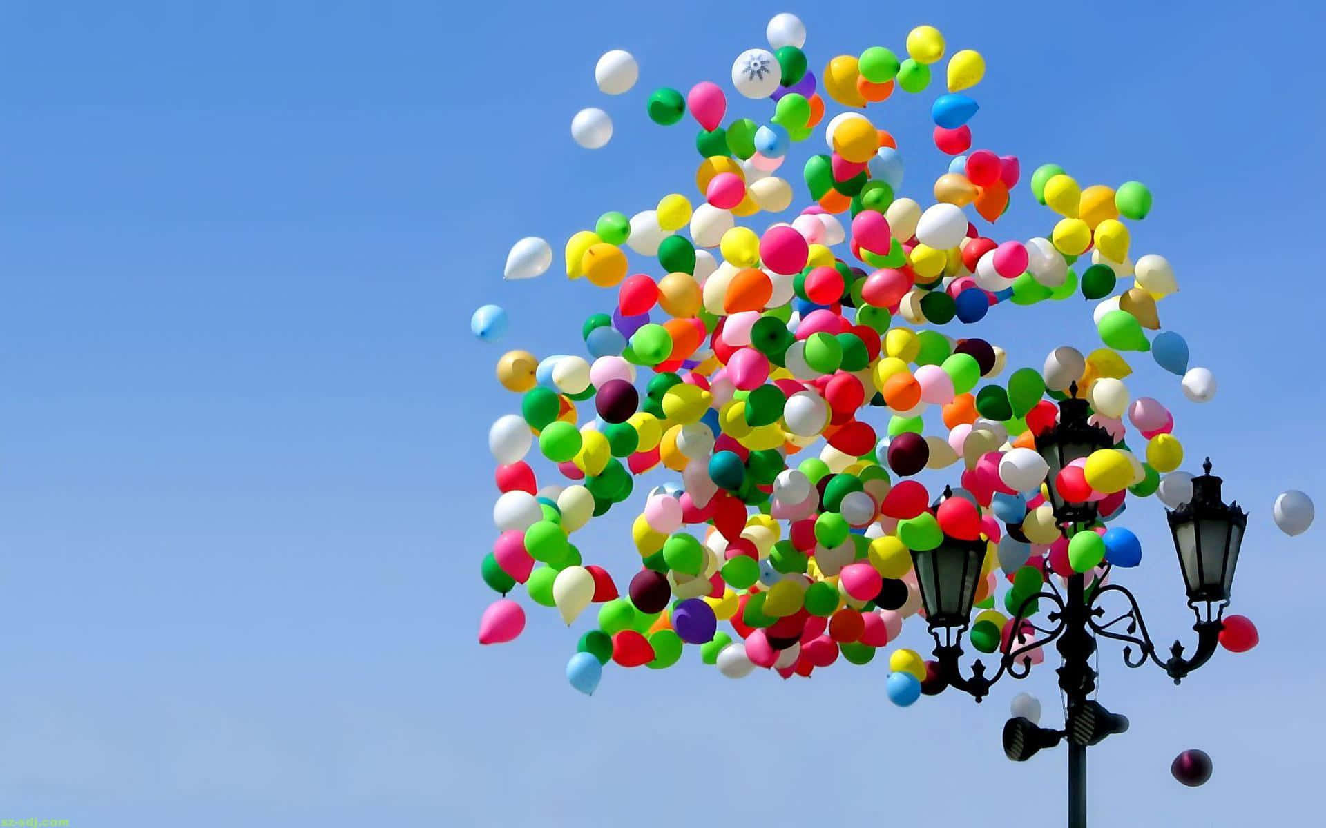 A Street Lamp With Many Balloons Flying In The Sky