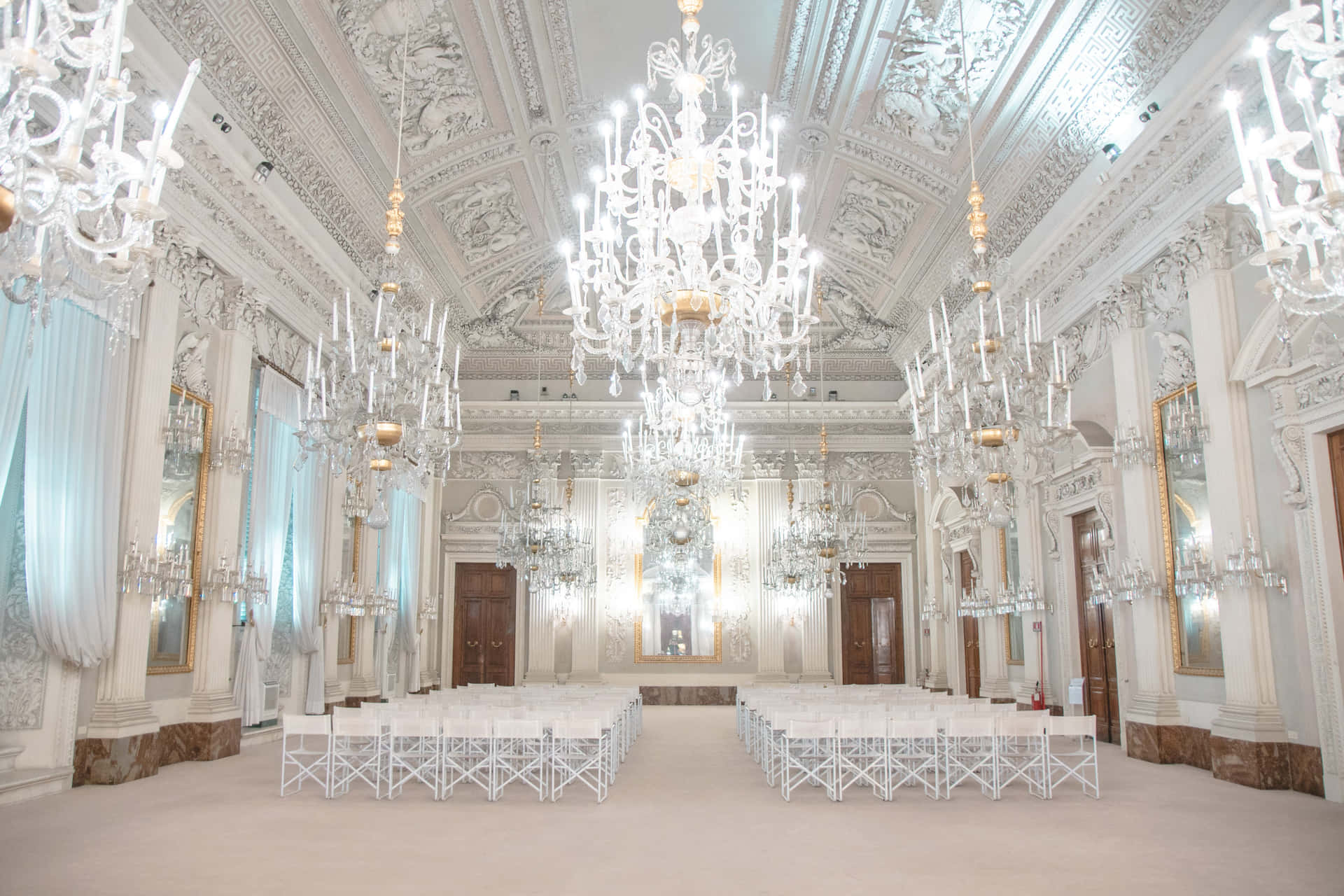 A Large Room With White Chairs And Chandeliers