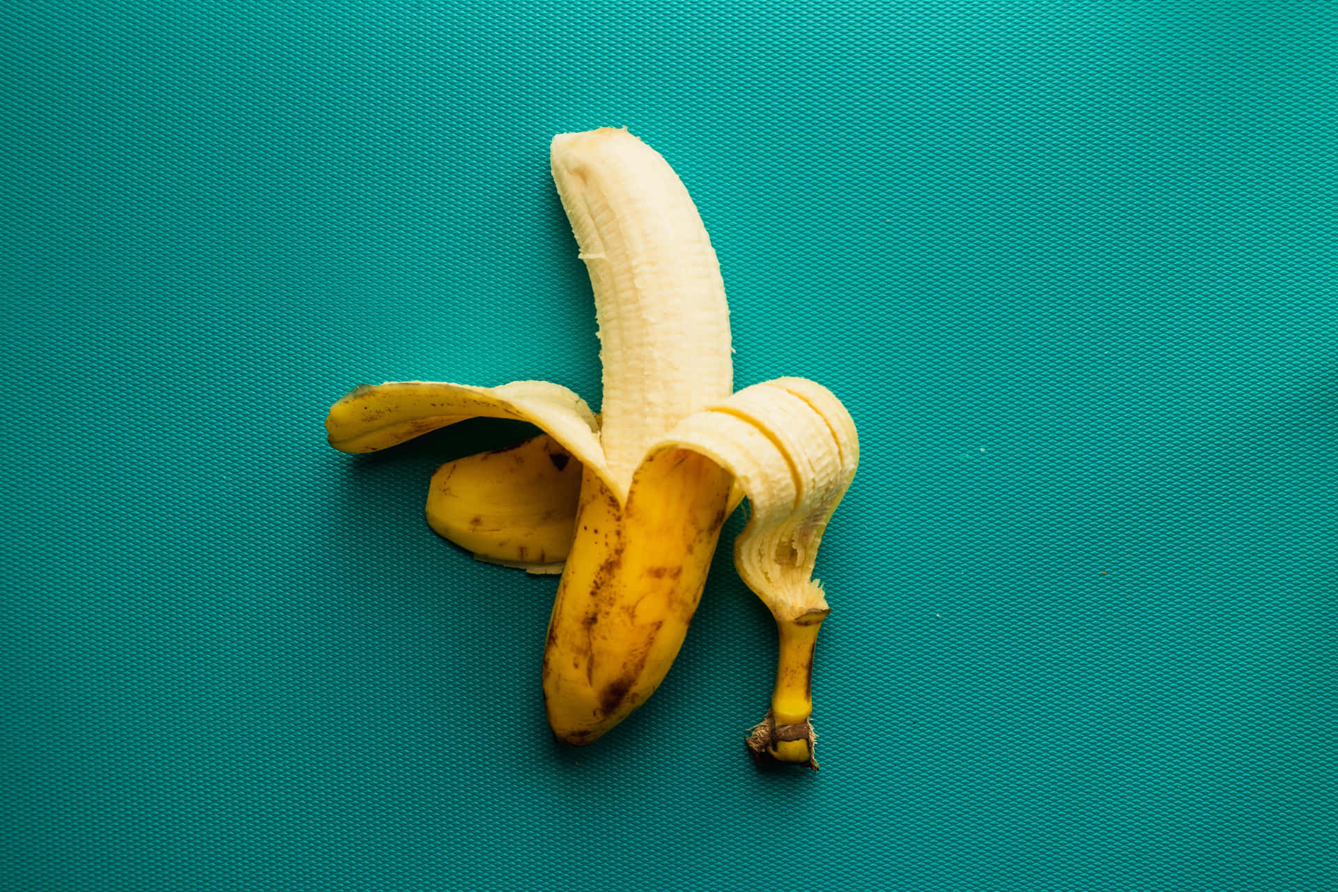 This juicy banana sits atop a brown wooden background