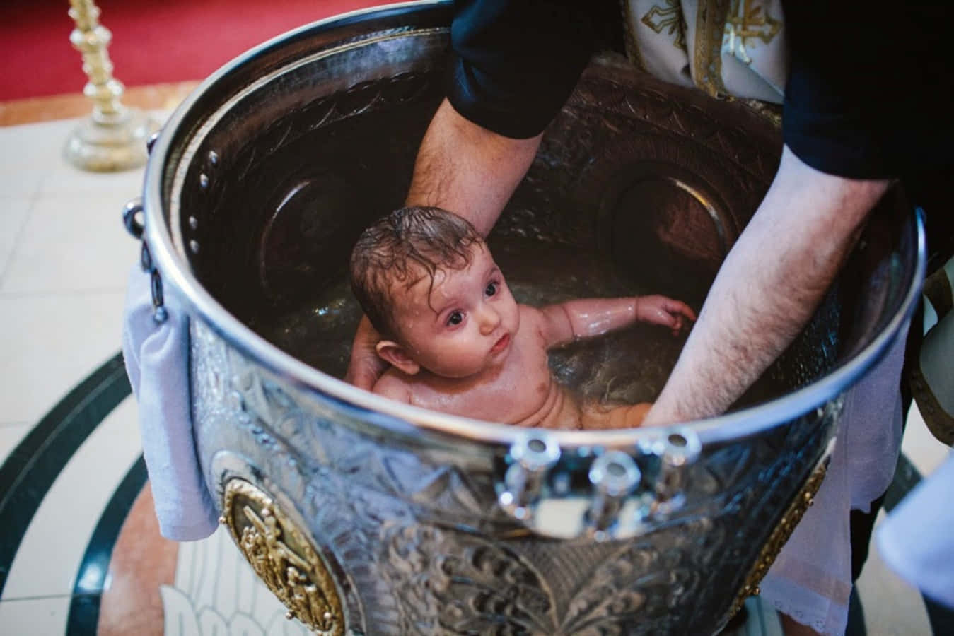 A Baby Being Baptized In A Large Metal Tub