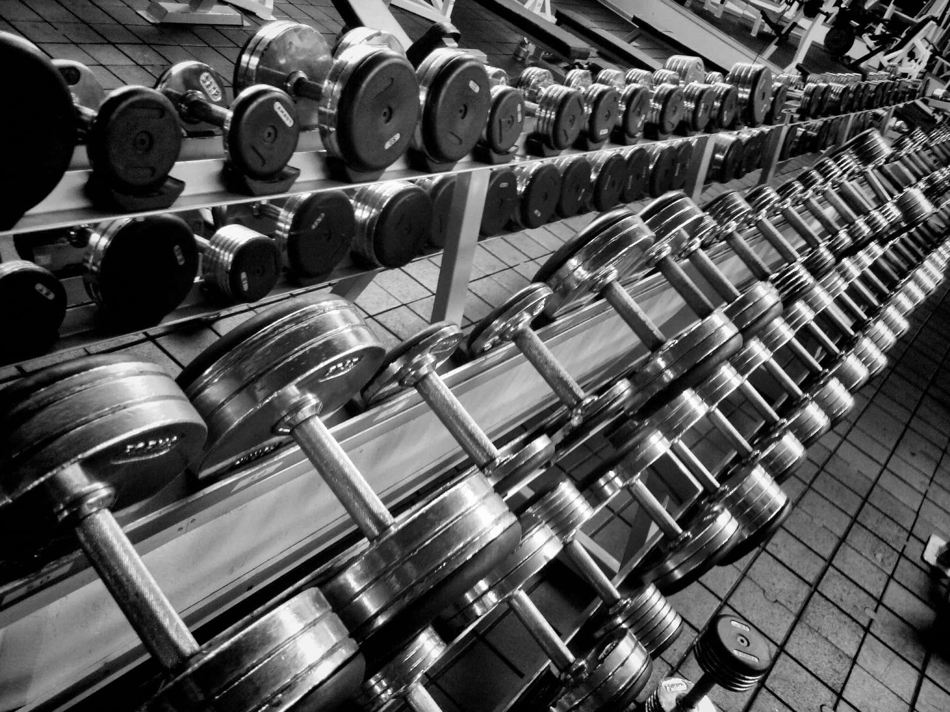 A Black And White Photo Of A Gym With Dumbbells