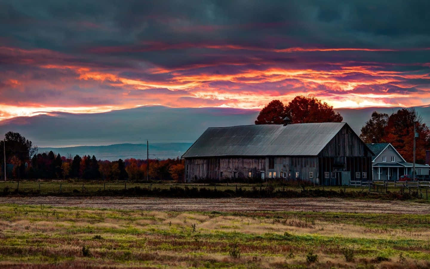 Enjoy the beauty of nature with this gorgeous sunset view of a barn.
