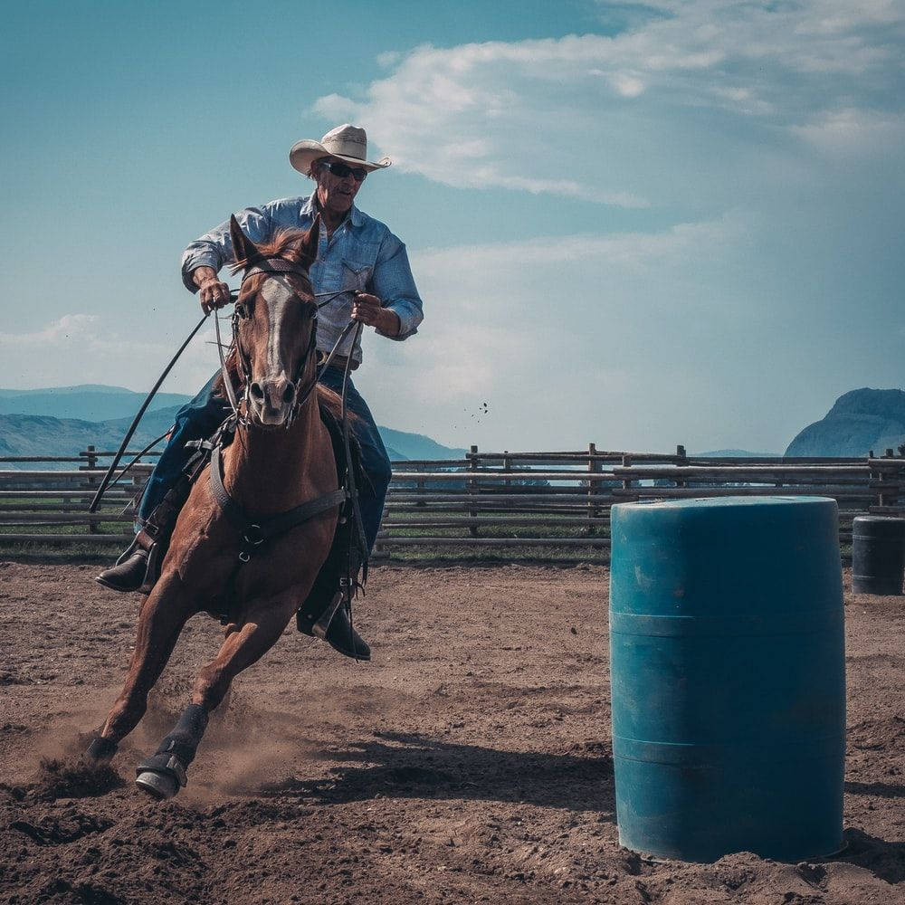 En cowgirl ride på en hest i en tønde race. Wallpaper