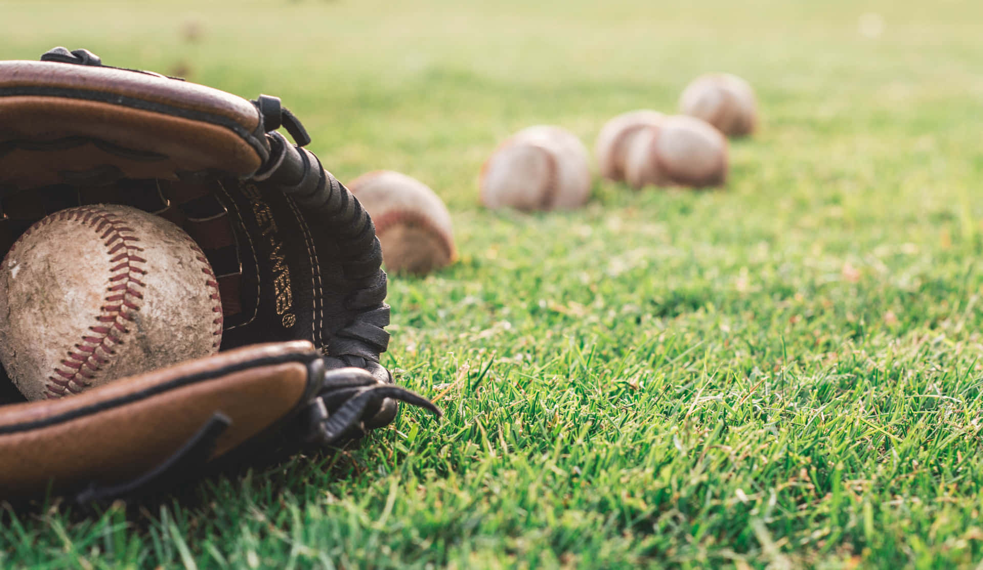 A high-quality image of baseball gloves stacked together on a wooden background Wallpaper