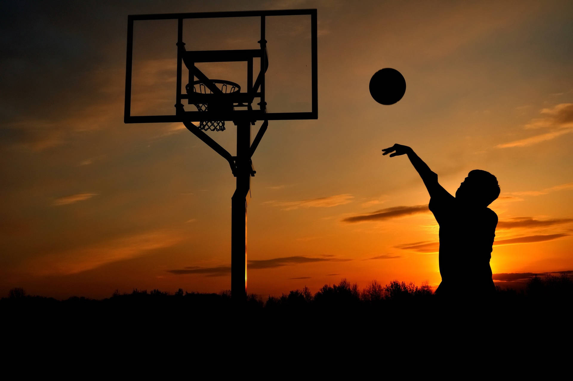 Basketballplatzspielerim Sonnenuntergang Wallpaper