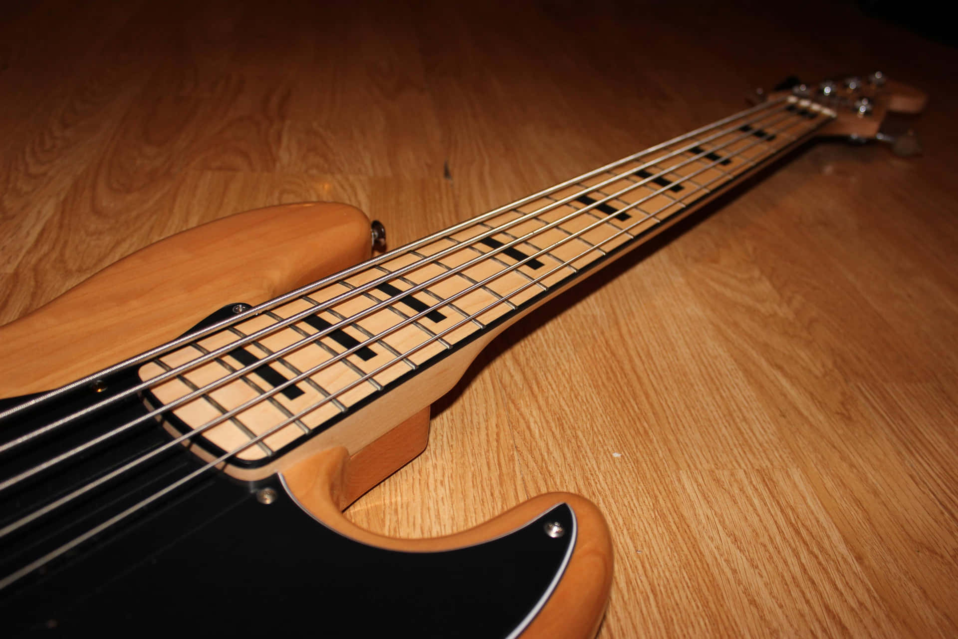 A Bass Guitar Is Sitting On A Wooden Floor Wallpaper