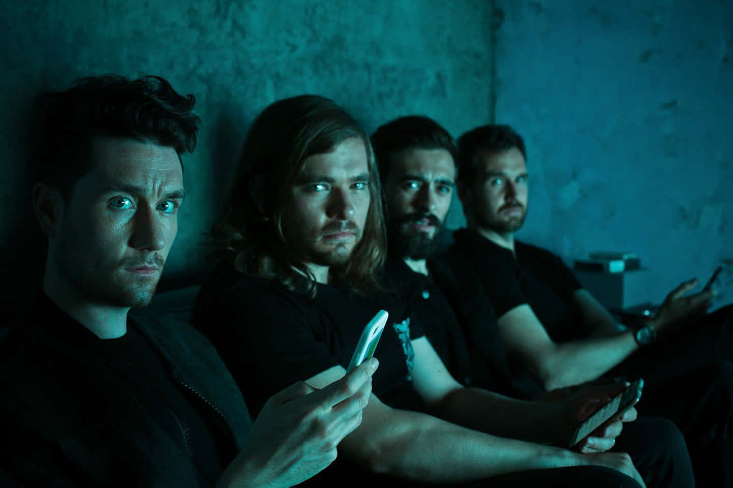 A Group Of Men Sitting In A Dark Room