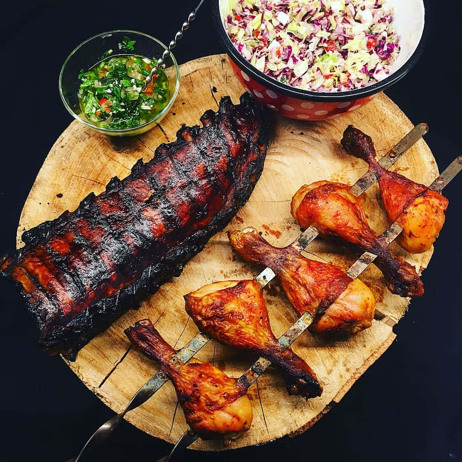 A Wooden Board With Ribs, Chicken And Salad