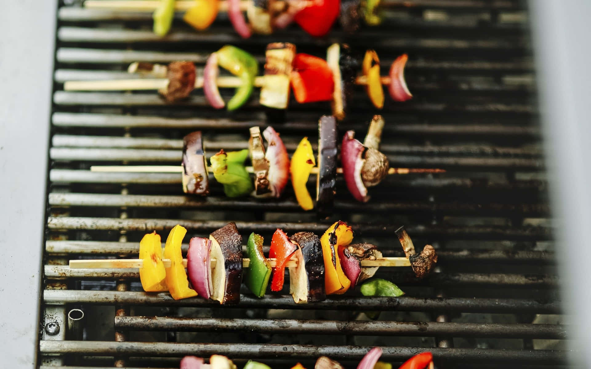 A Grill With Skewers Of Vegetables On It