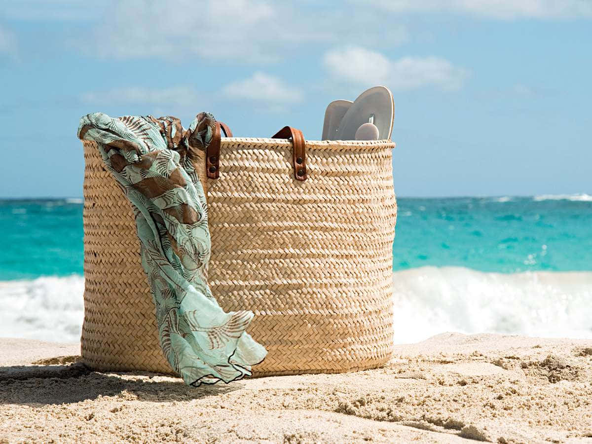 Caption: A Stylish Beach Bag on a Sun-Kissed Shore Wallpaper