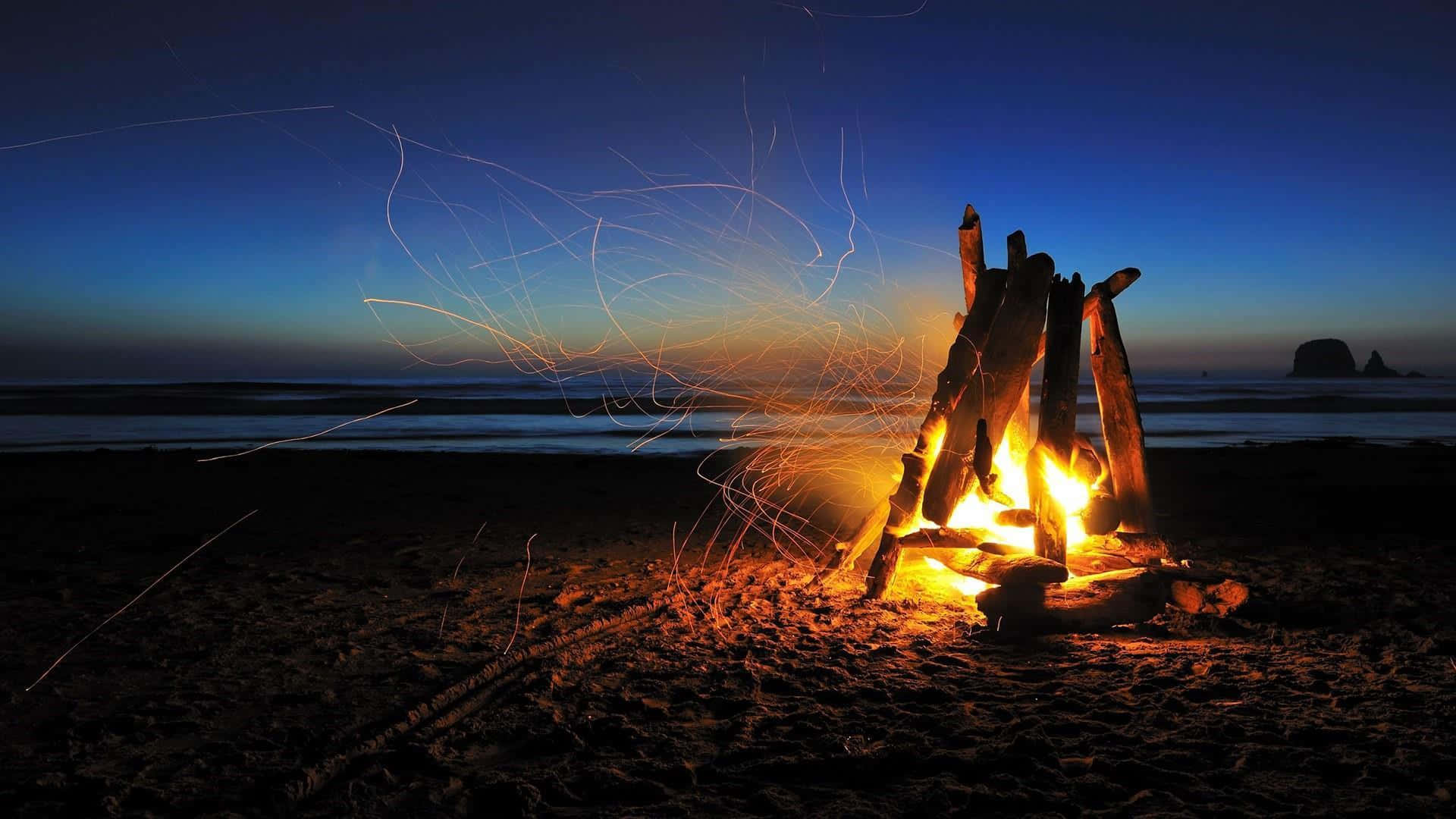 Cozy Beach Bonfire During Sunset Wallpaper