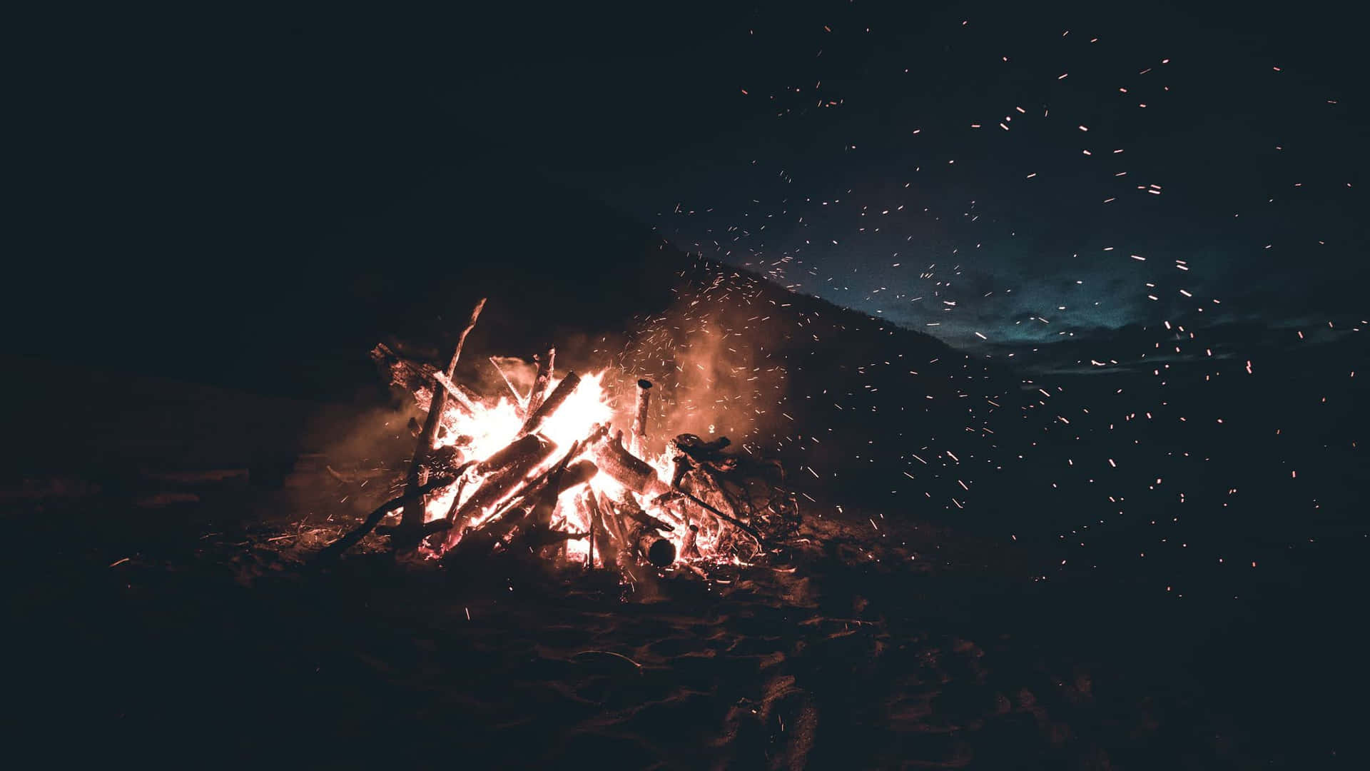 A beach bonfire under a mesmerizing sky Wallpaper