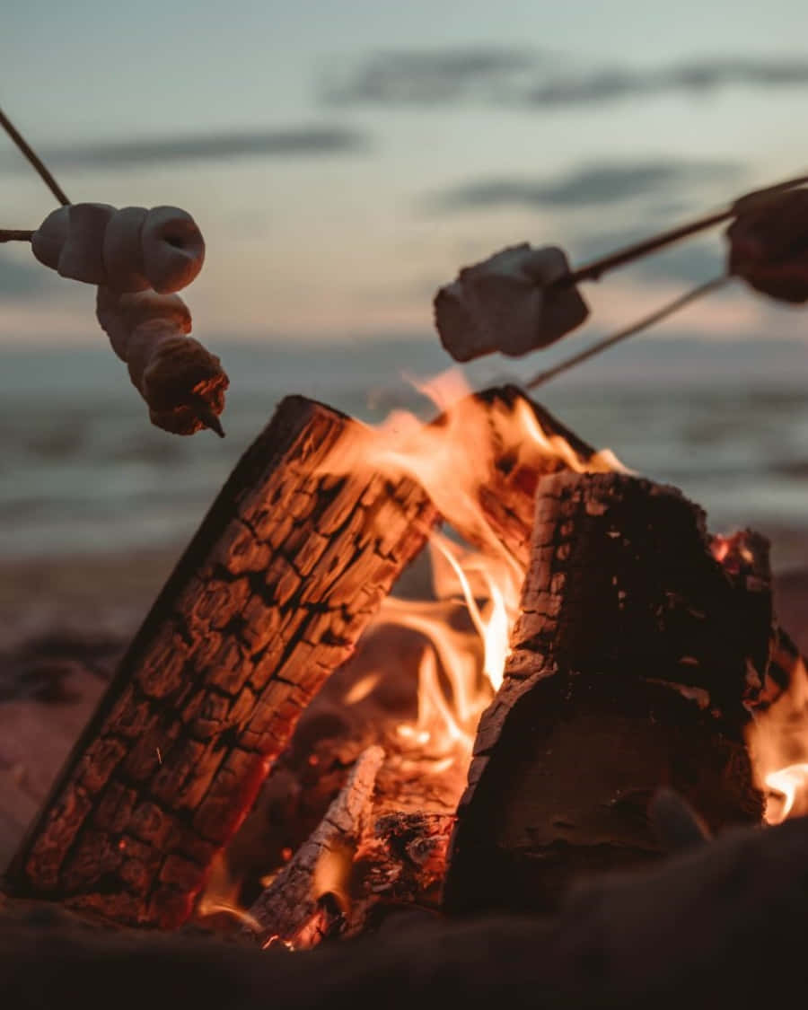 Ignite a Beach Adventure - Friends Enjoying a Beach Bonfire Under the Stars Wallpaper