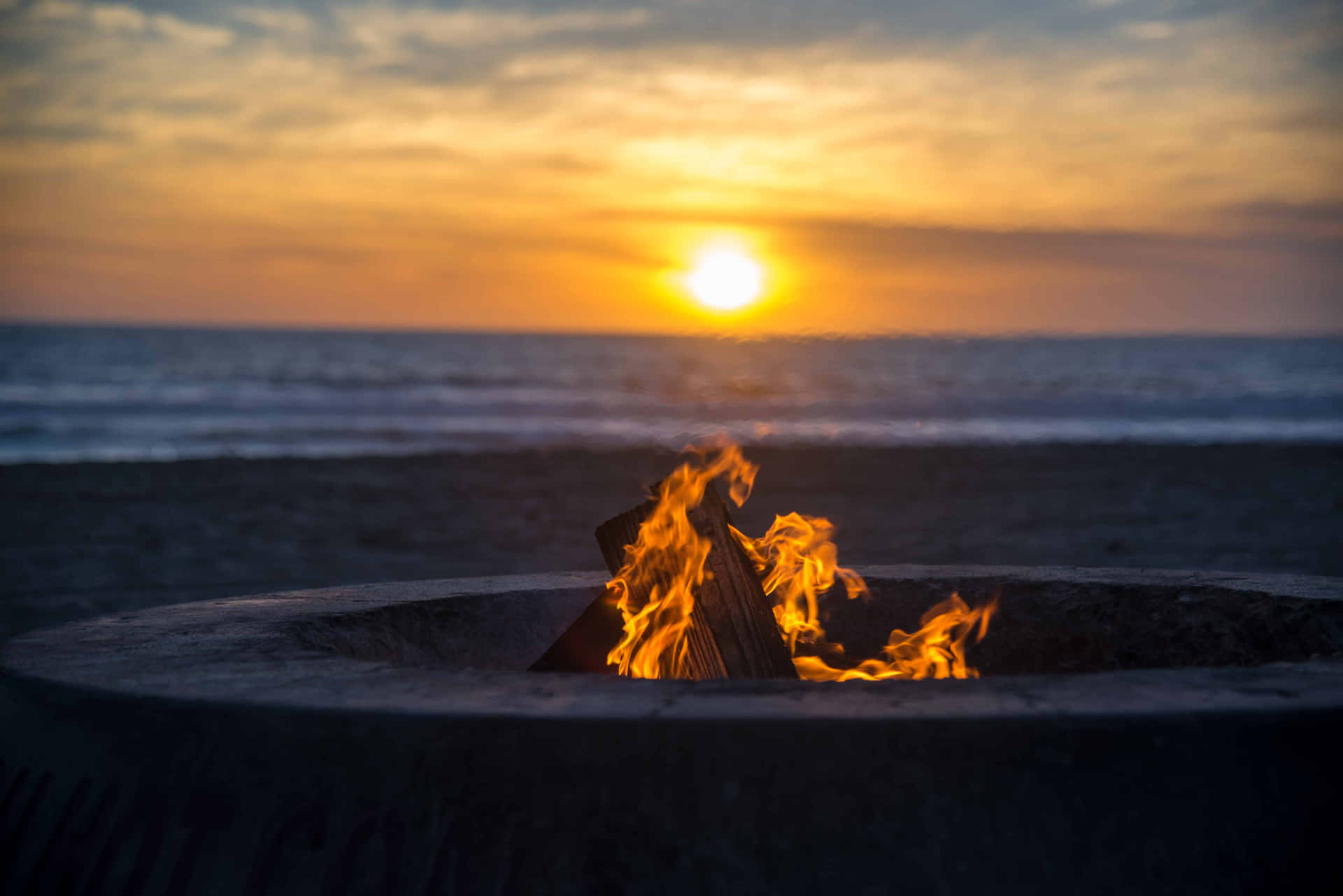 Friends Enjoying Warm Beach Campfire During A Beautiful Sunset Wallpaper