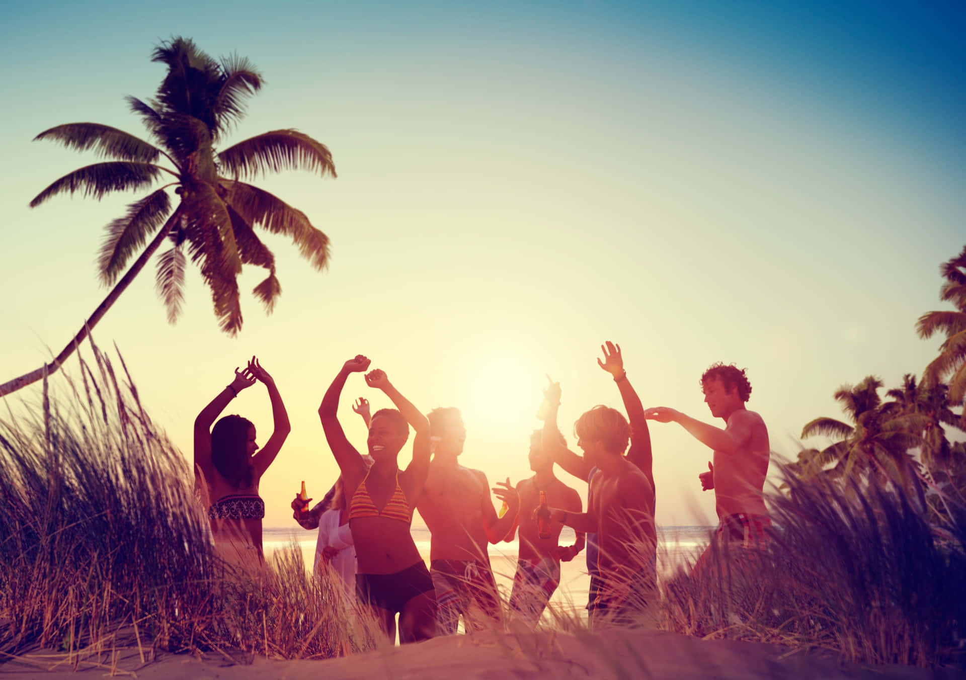 Beach Dance Party Under a Magical Sunset Wallpaper