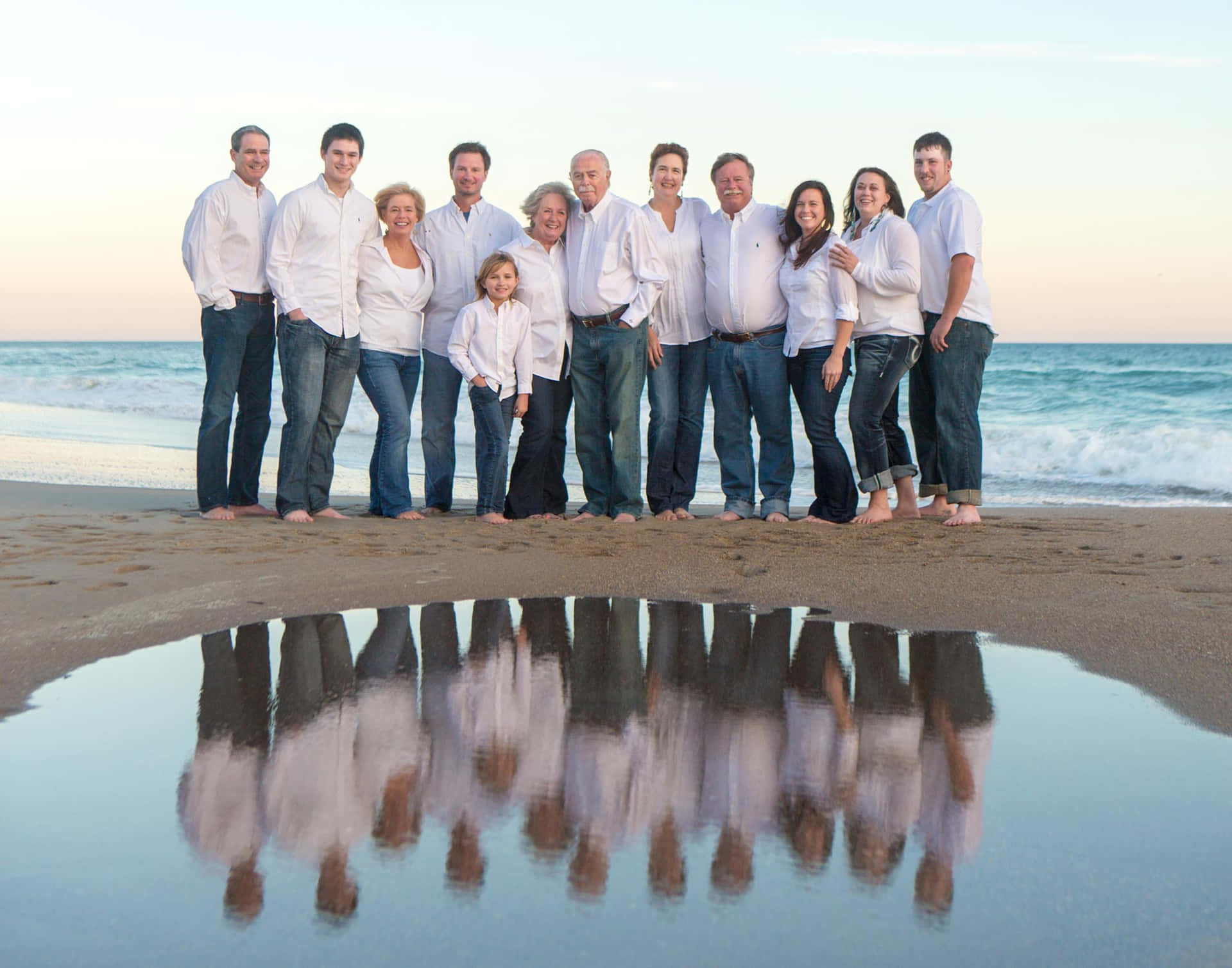 A Family Is Posing On The Beach With Their Reflection In The Water
