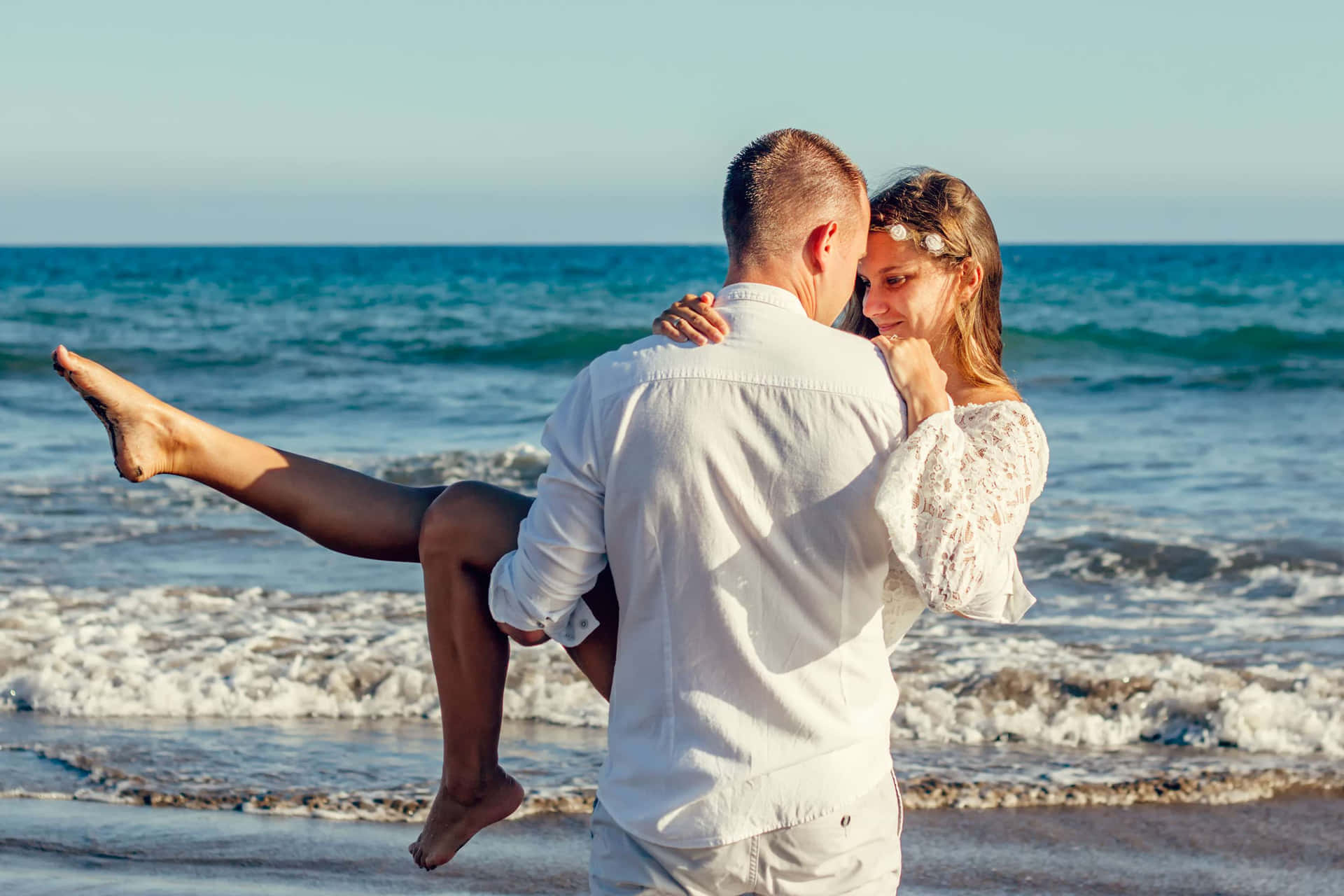 Couple Embracing on a Sunset Beach Wallpaper