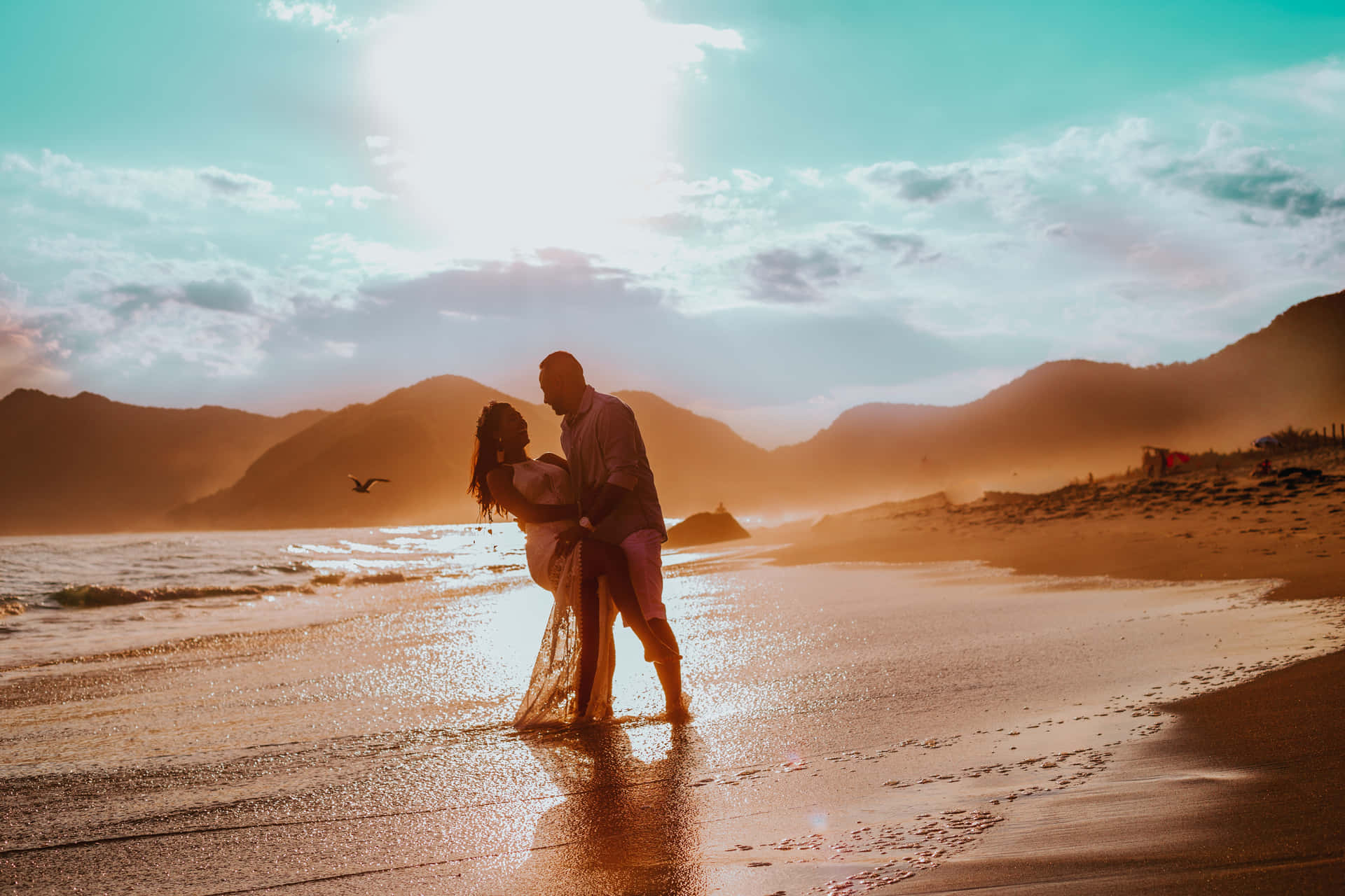 Romantic couple enjoying a beautiful sunset on the beach Wallpaper