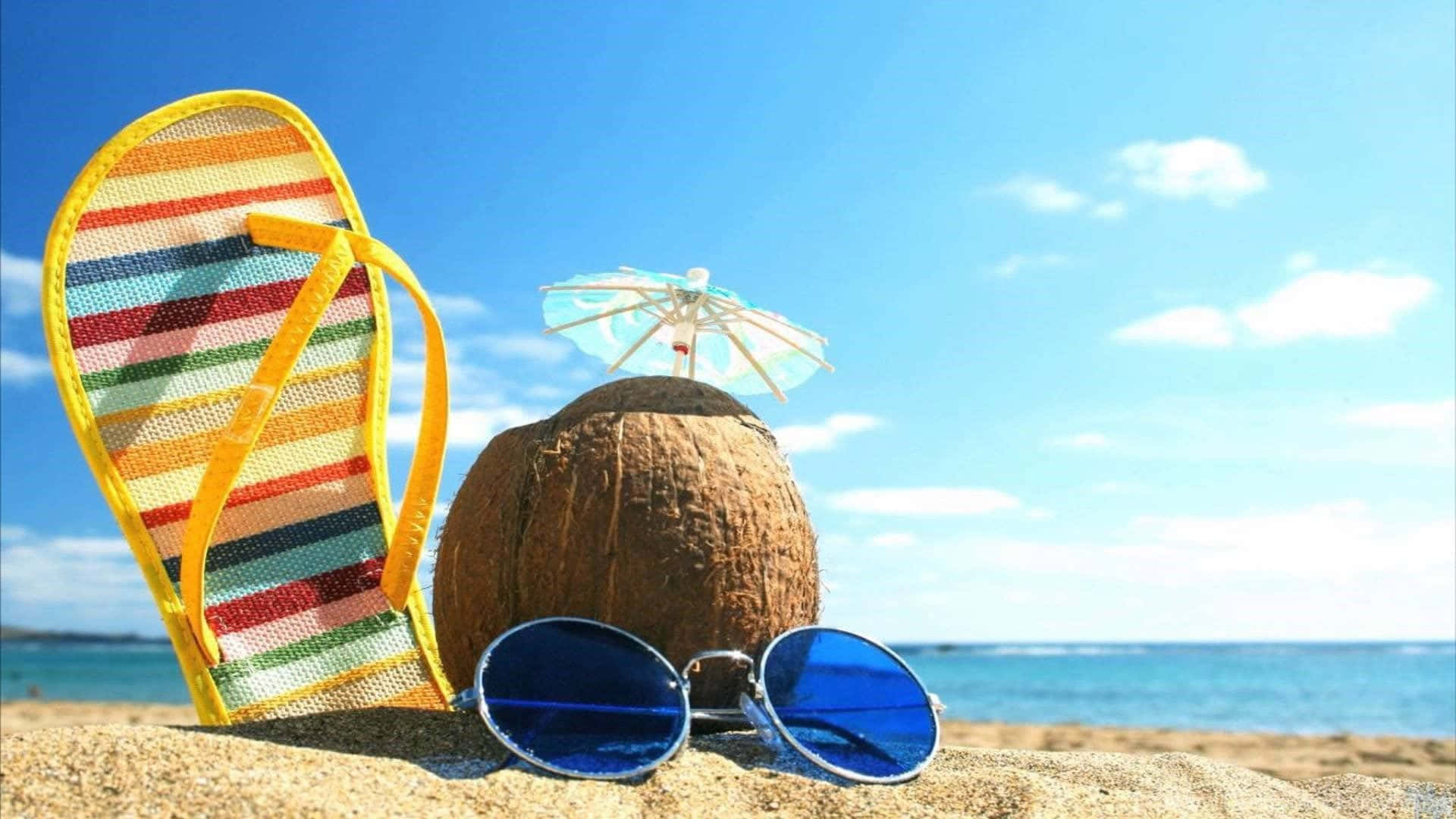 Et par flip-flops, solbriller og en paraply på stranden