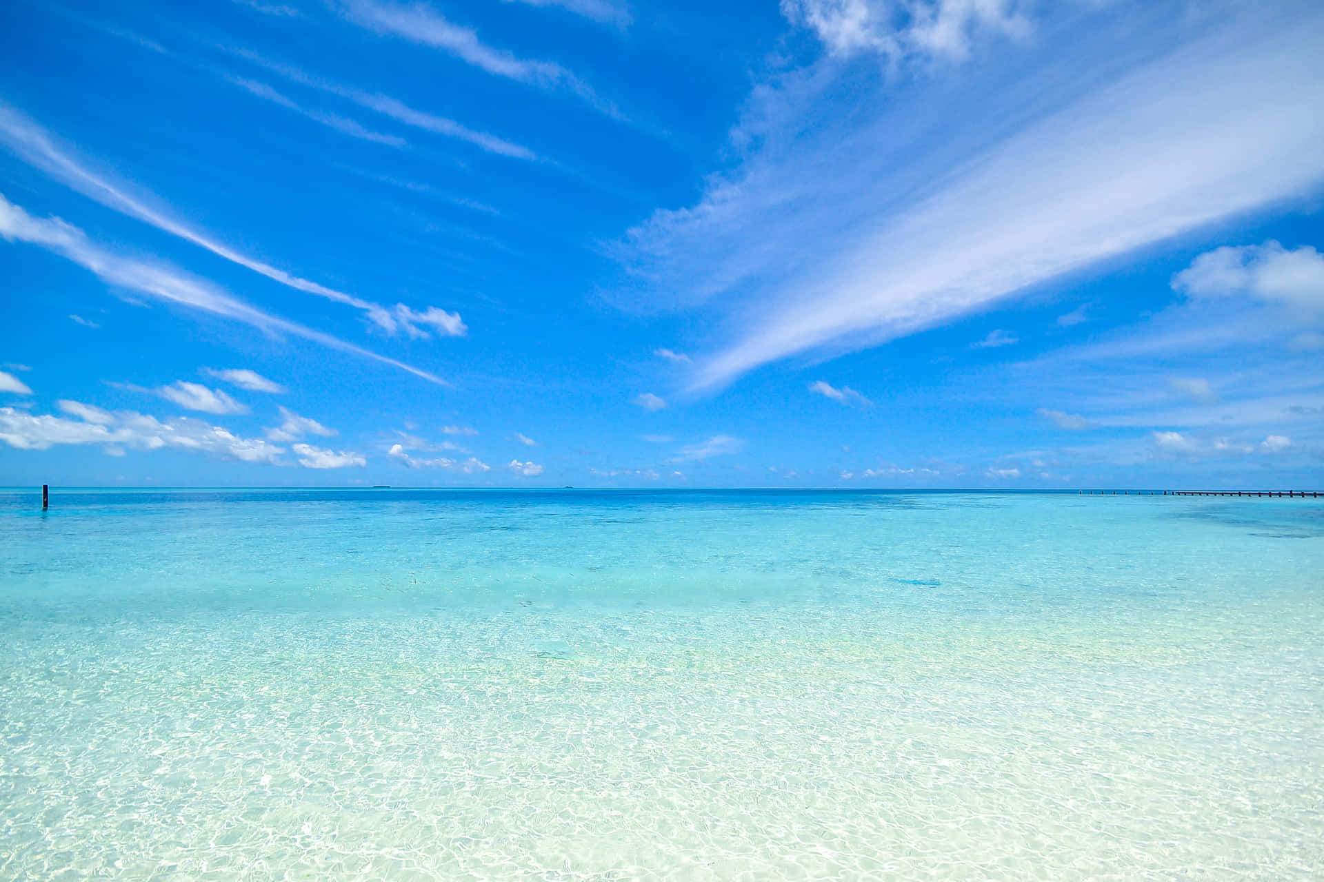Få et kort øjeblik af vidunderlig skønhed med en fredfyldt strand og skyet blå himmel. Wallpaper