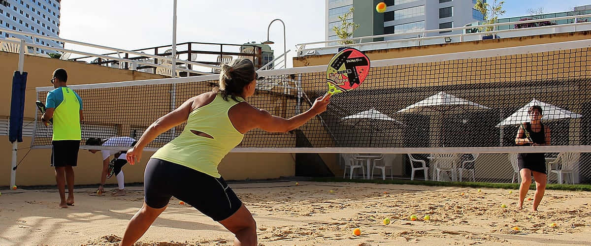 Exciting Beach Tennis Match on a Sunny Day Wallpaper