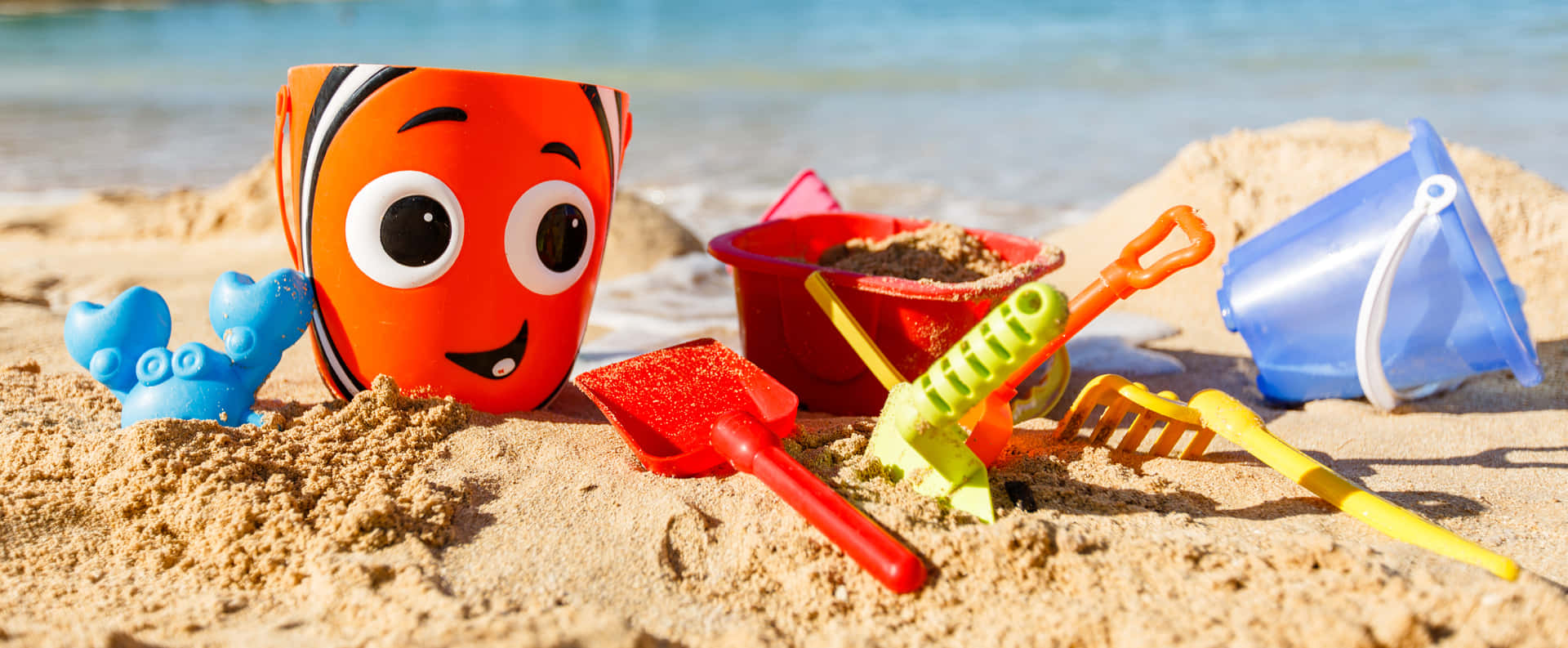 A Colorful Collection of Beach Toys on the Sandy Shore Wallpaper