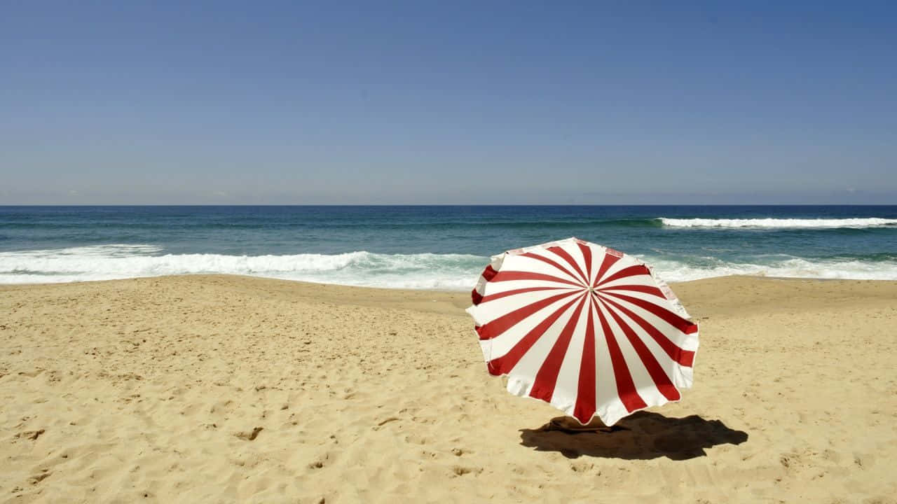 Vibrant beach umbrella providing shade on a sunny day Wallpaper